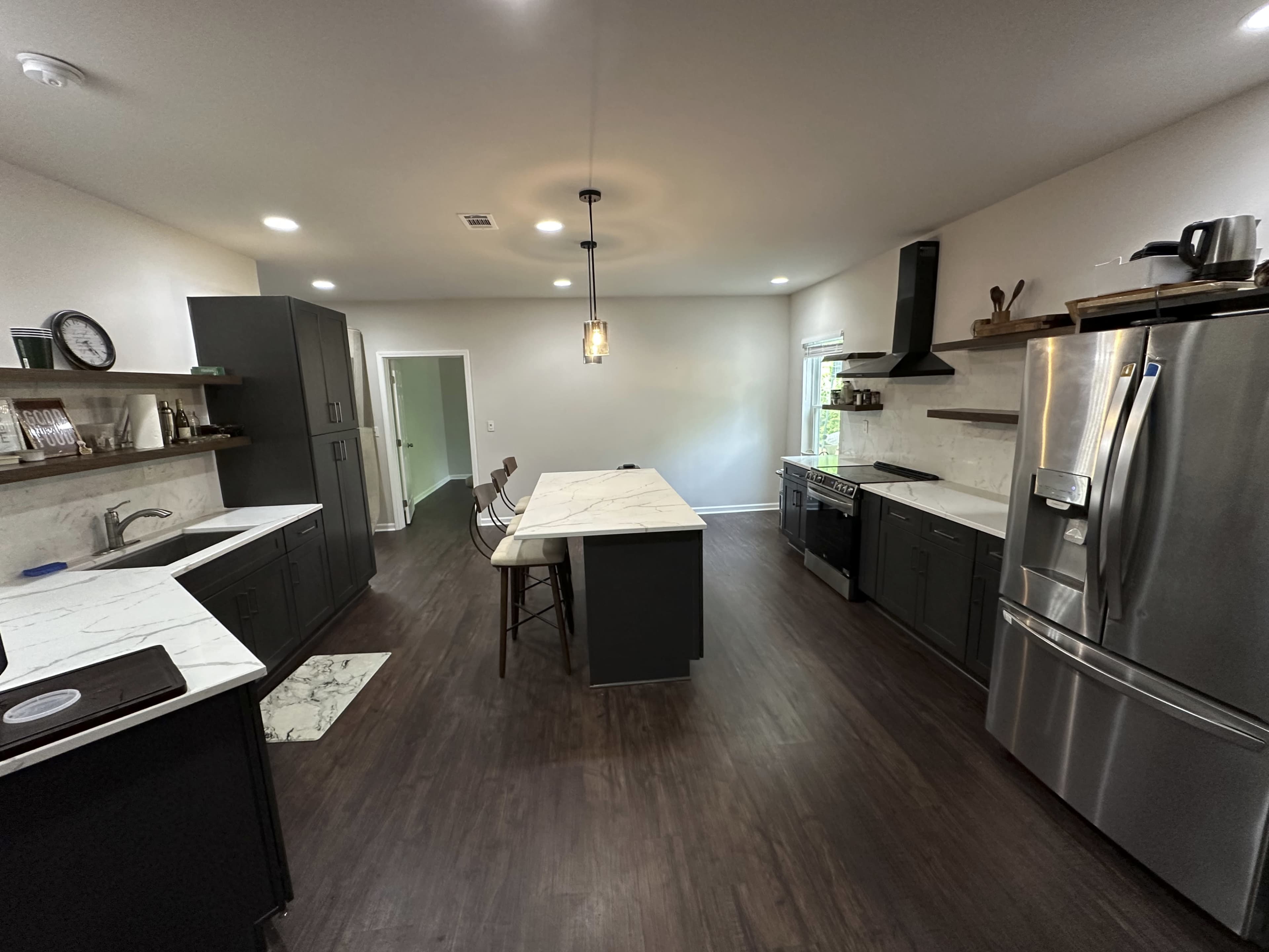 The kitchen features a central island with a marble countertop, dark cabinets, and stainless steel appliances.