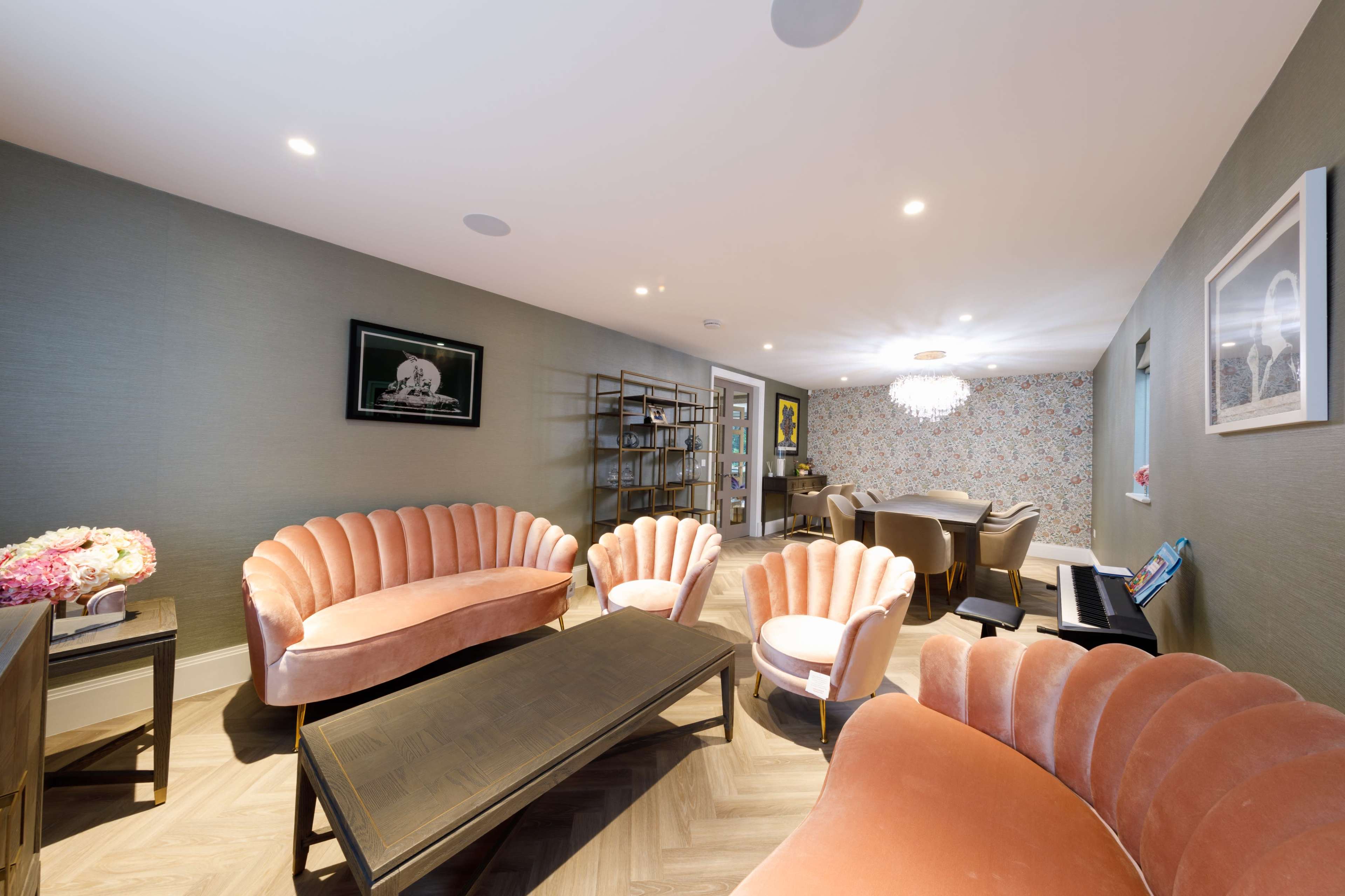 A modern living room with upholstered seating, a wooden coffee table, and a dining area in the background.