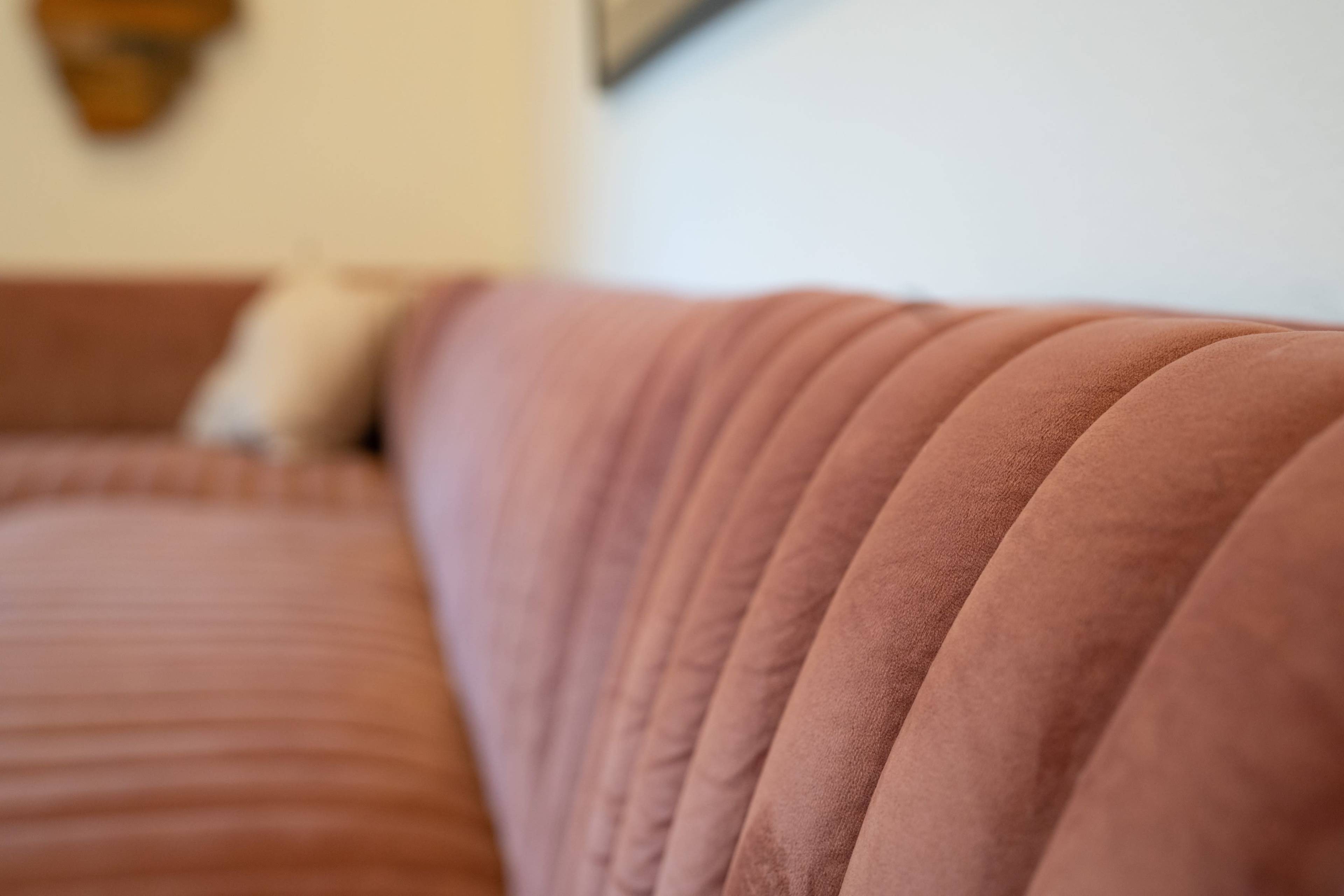 A close-up of a pink velvet sofa with tufted upholstery.