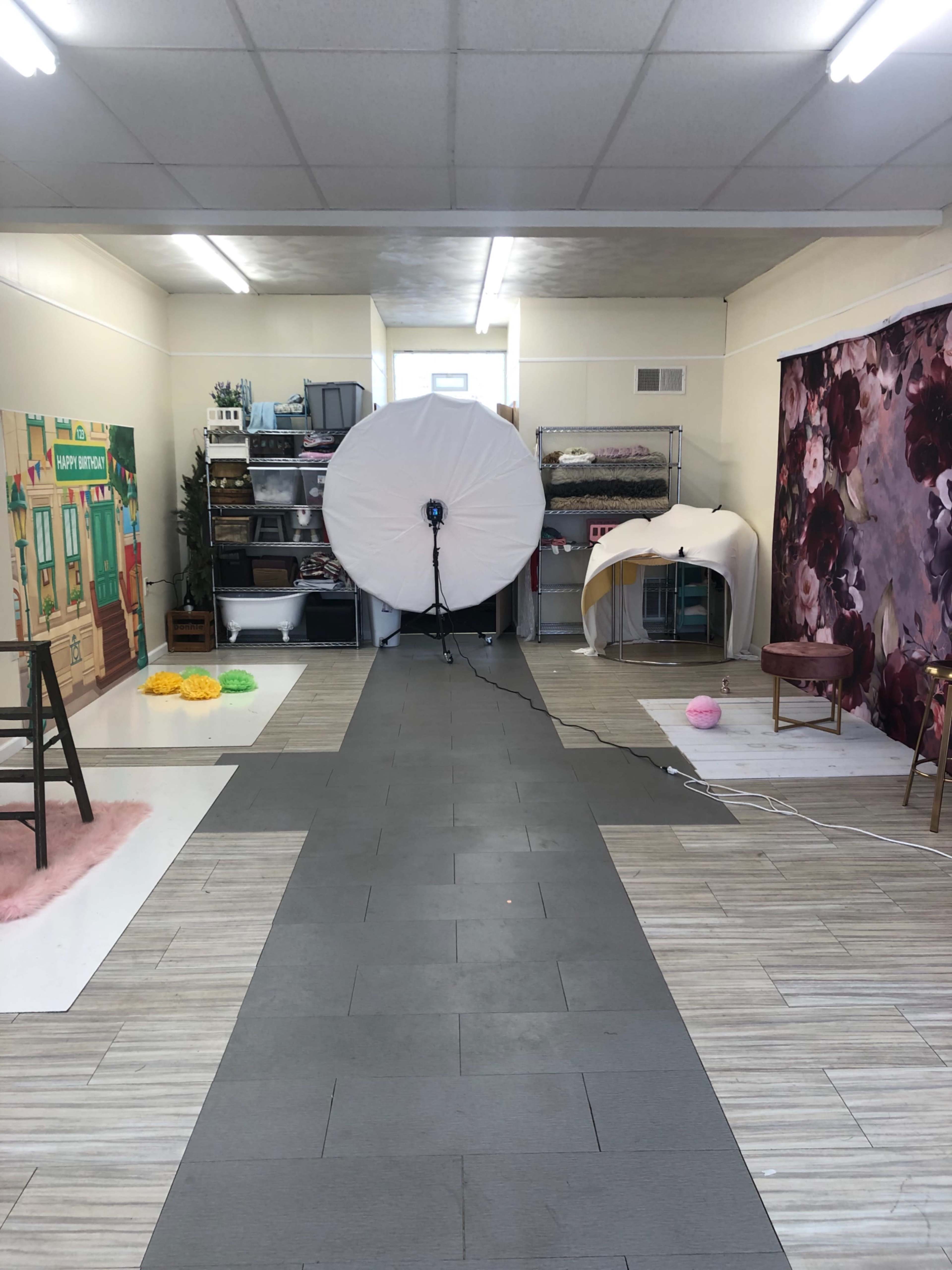 A photography studio with a large light setup at the center, surrounded by various props and backdrops.