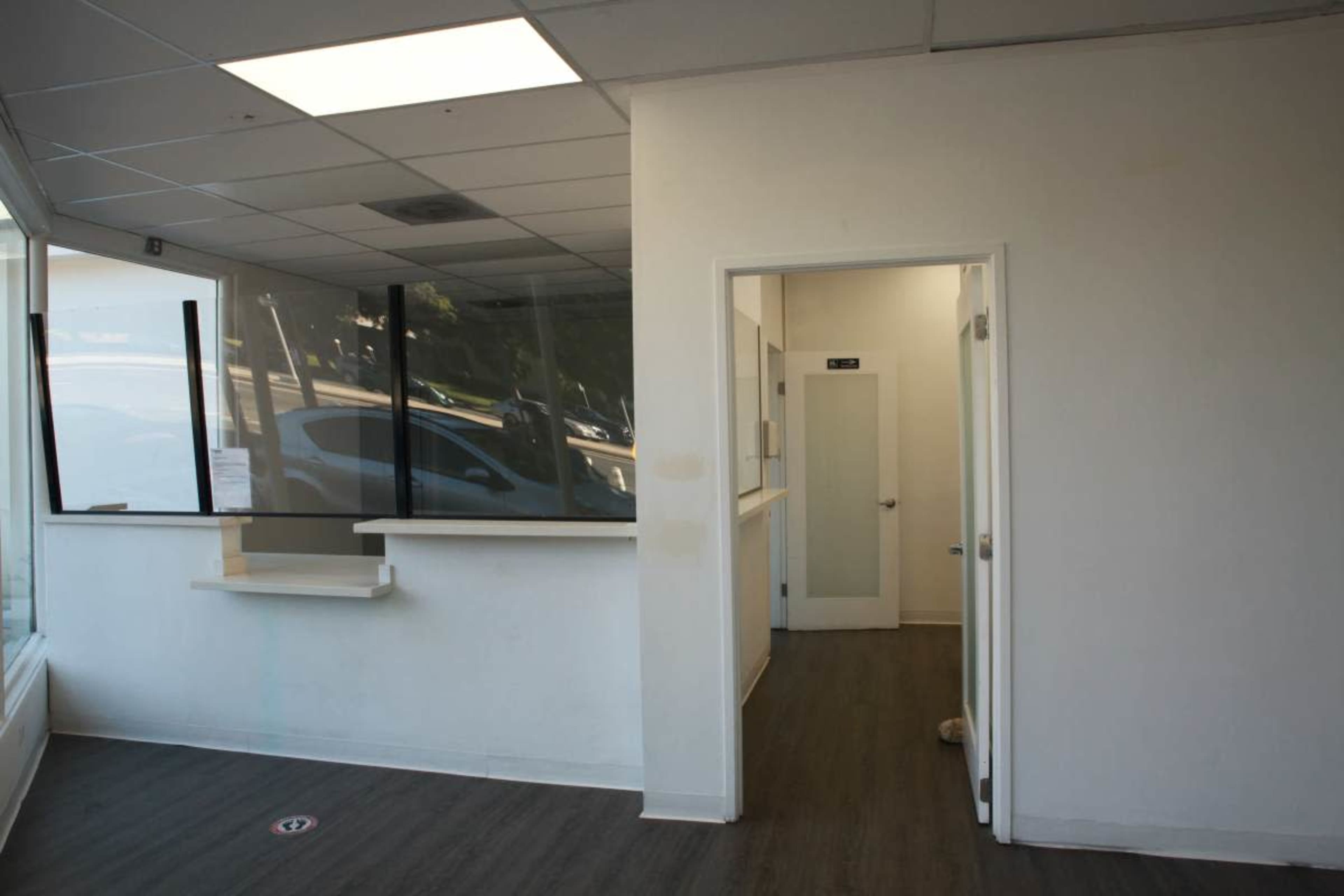 The image shows a vacant interior space with a counter on the left and a doorway leading to another room on the right.