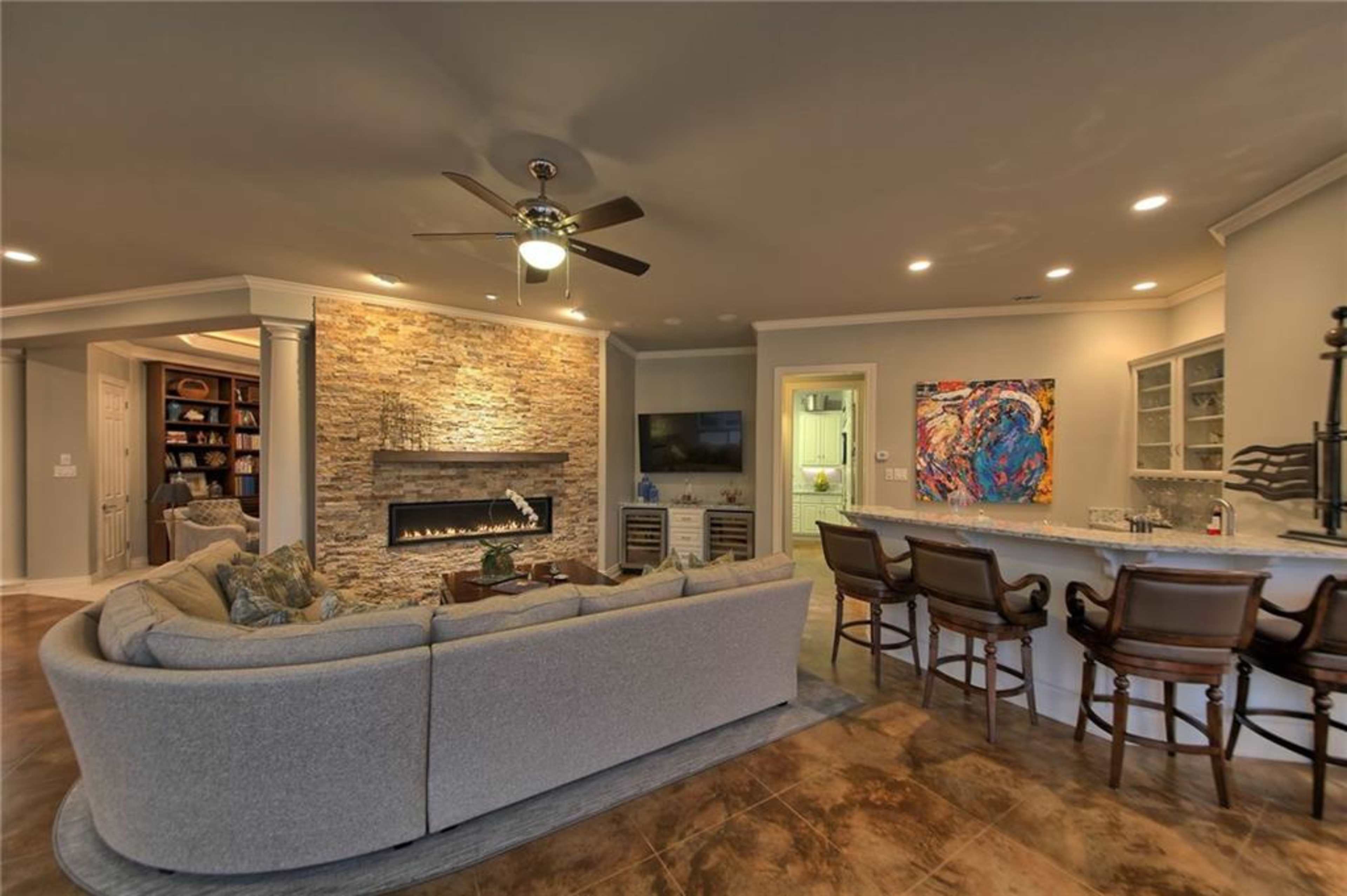 A modern living room with a stone accent wall, a fireplace, a sectional sofa, and a bar area with stools.