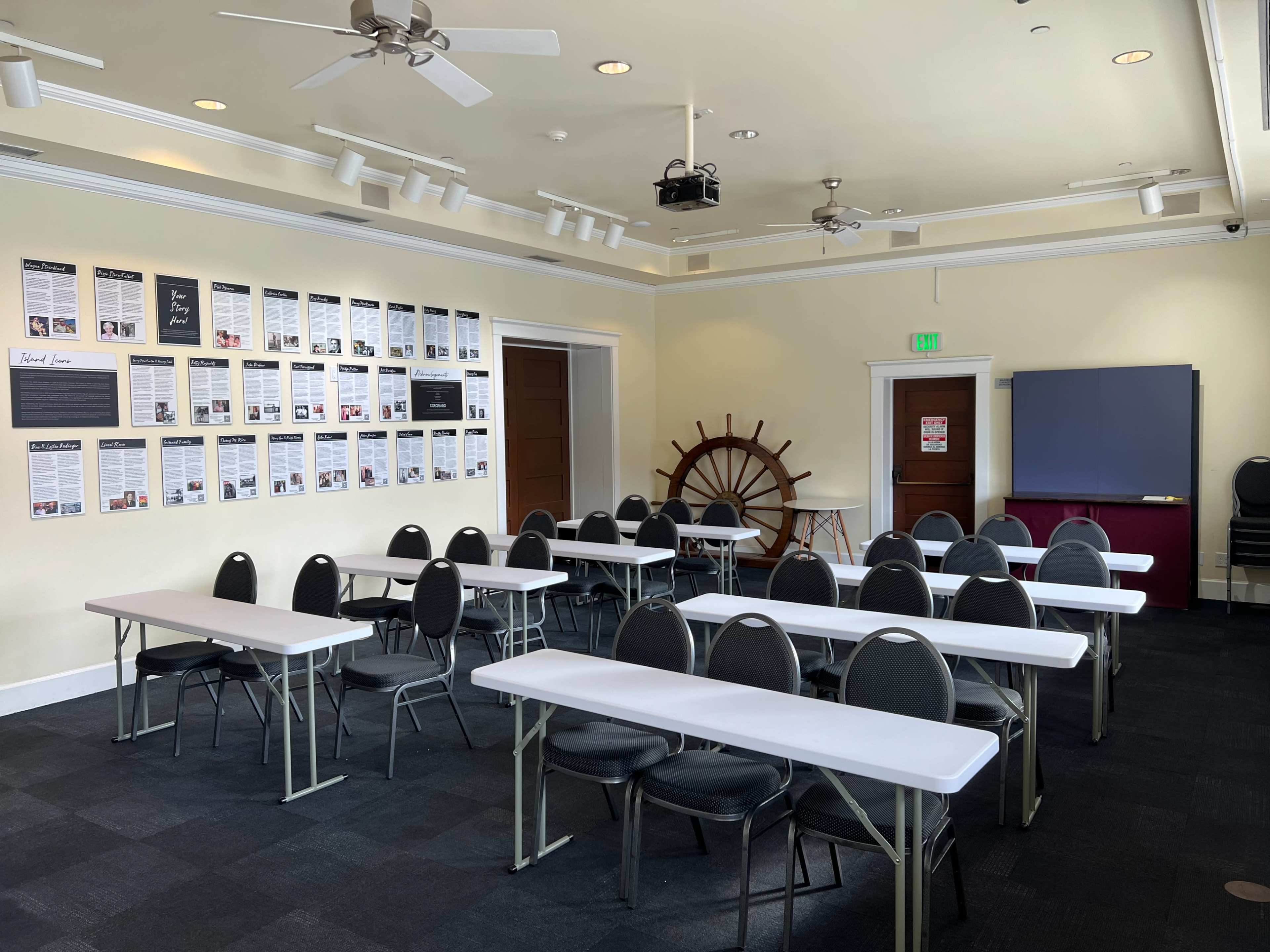 A conference room with multiple tables arranged in rows and a wall displaying various framed documents.