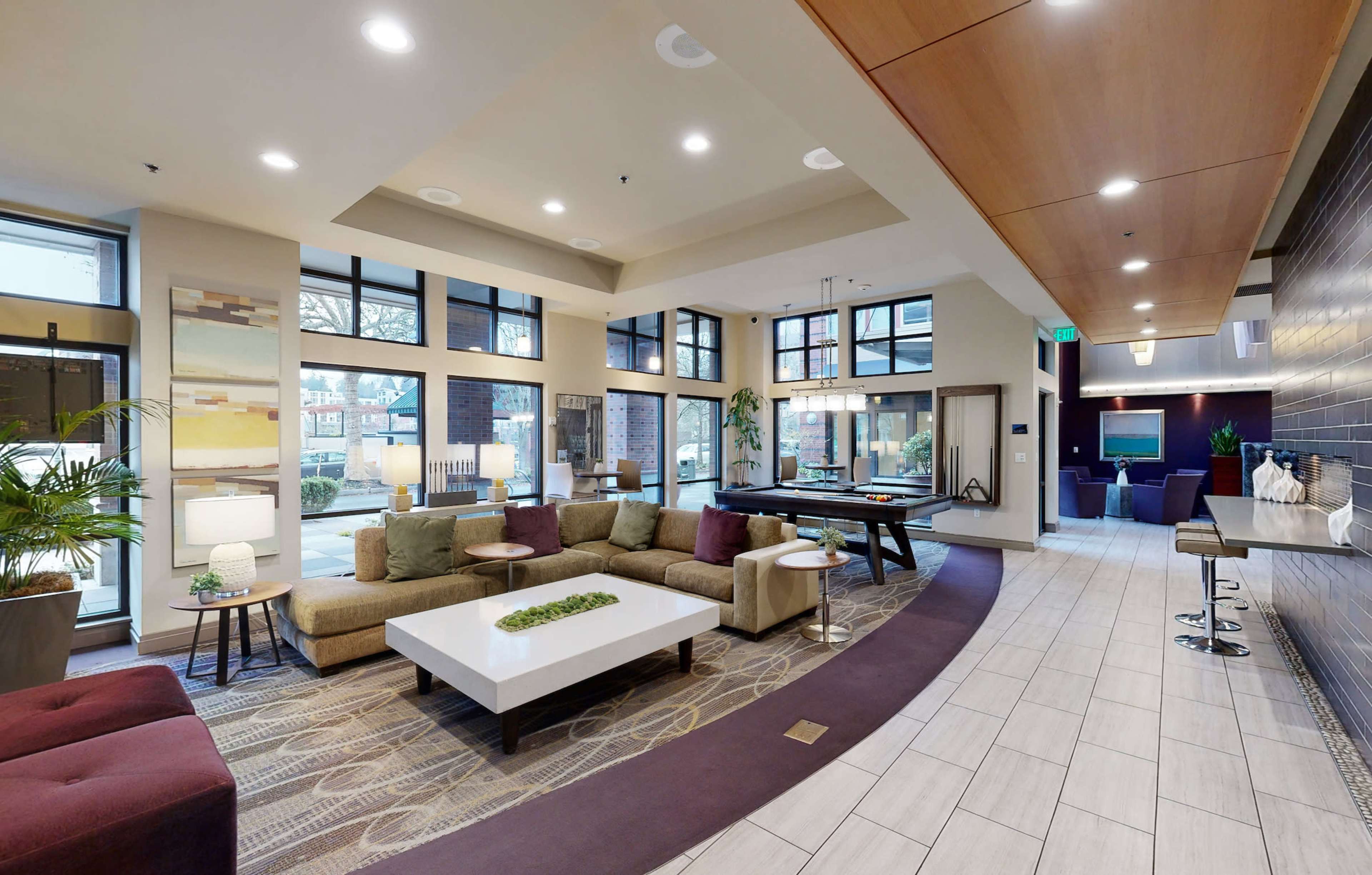 A modern lobby with sectional seating, a coffee table, and large windows that allow natural light to enter.