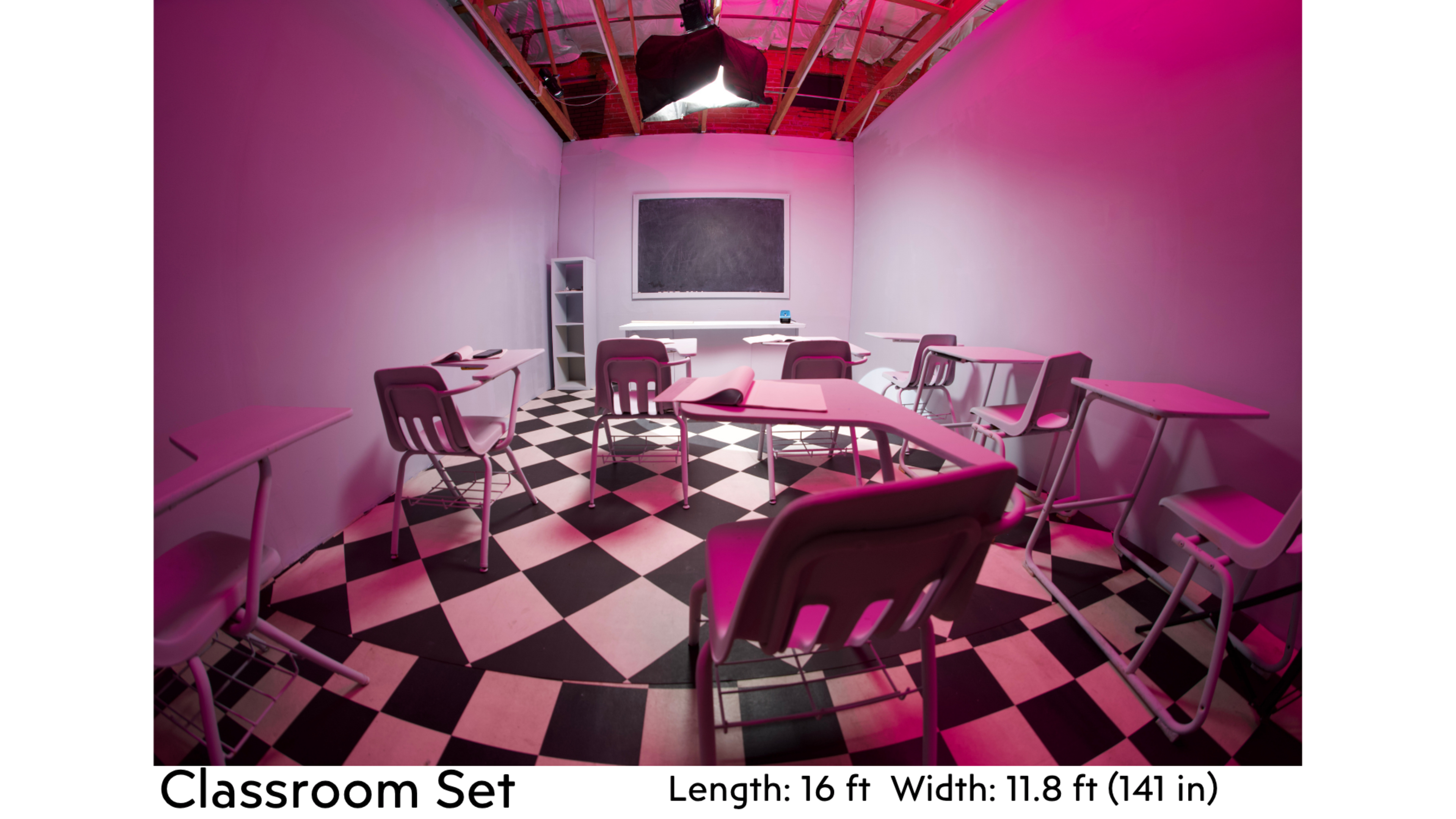 The image shows a classroom set with pink walls, a blackboard at the front, and several desks arranged in a grid pattern on a black and white checkered floor.