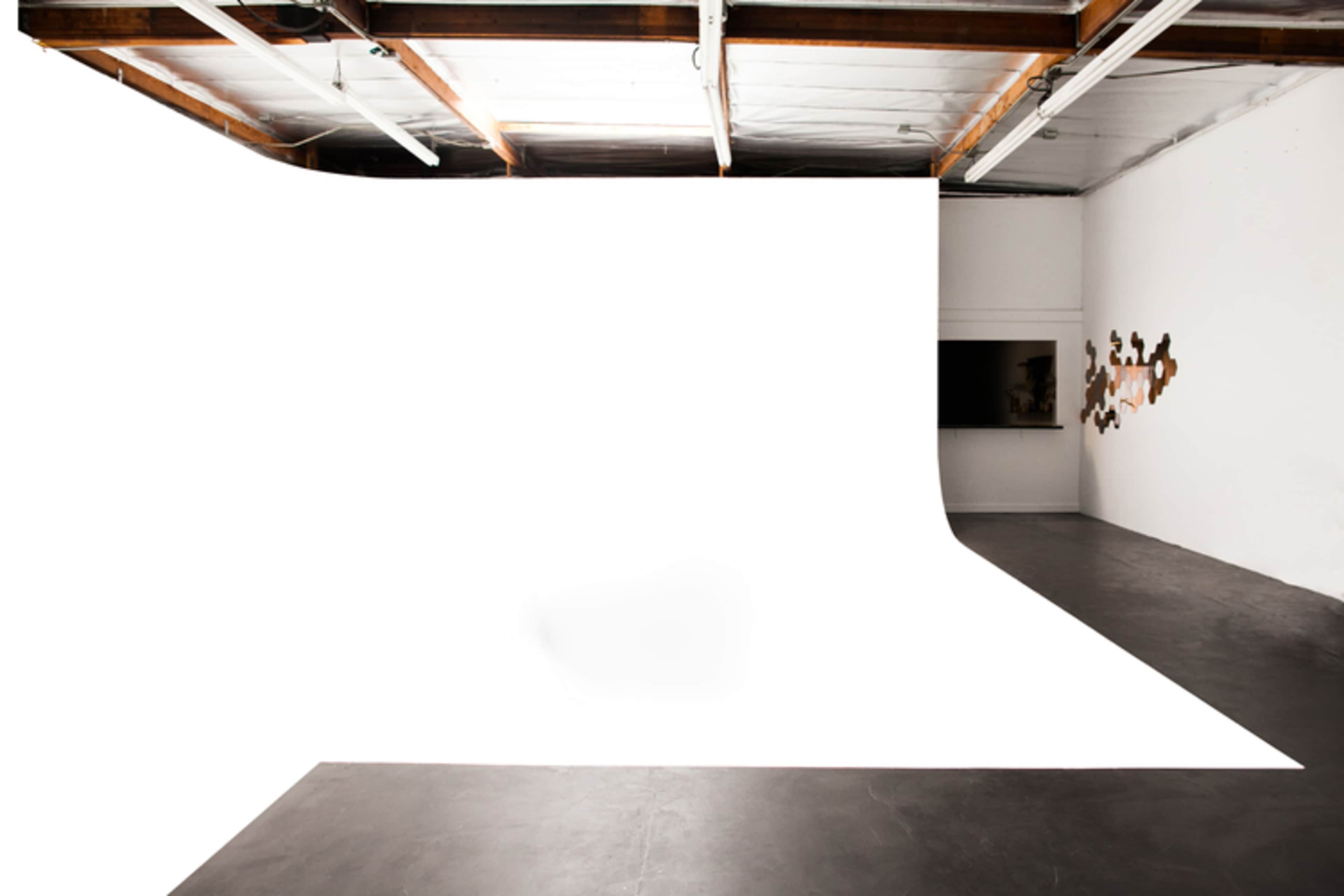 A spacious studio with a seamless white backdrop and polished concrete flooring.
