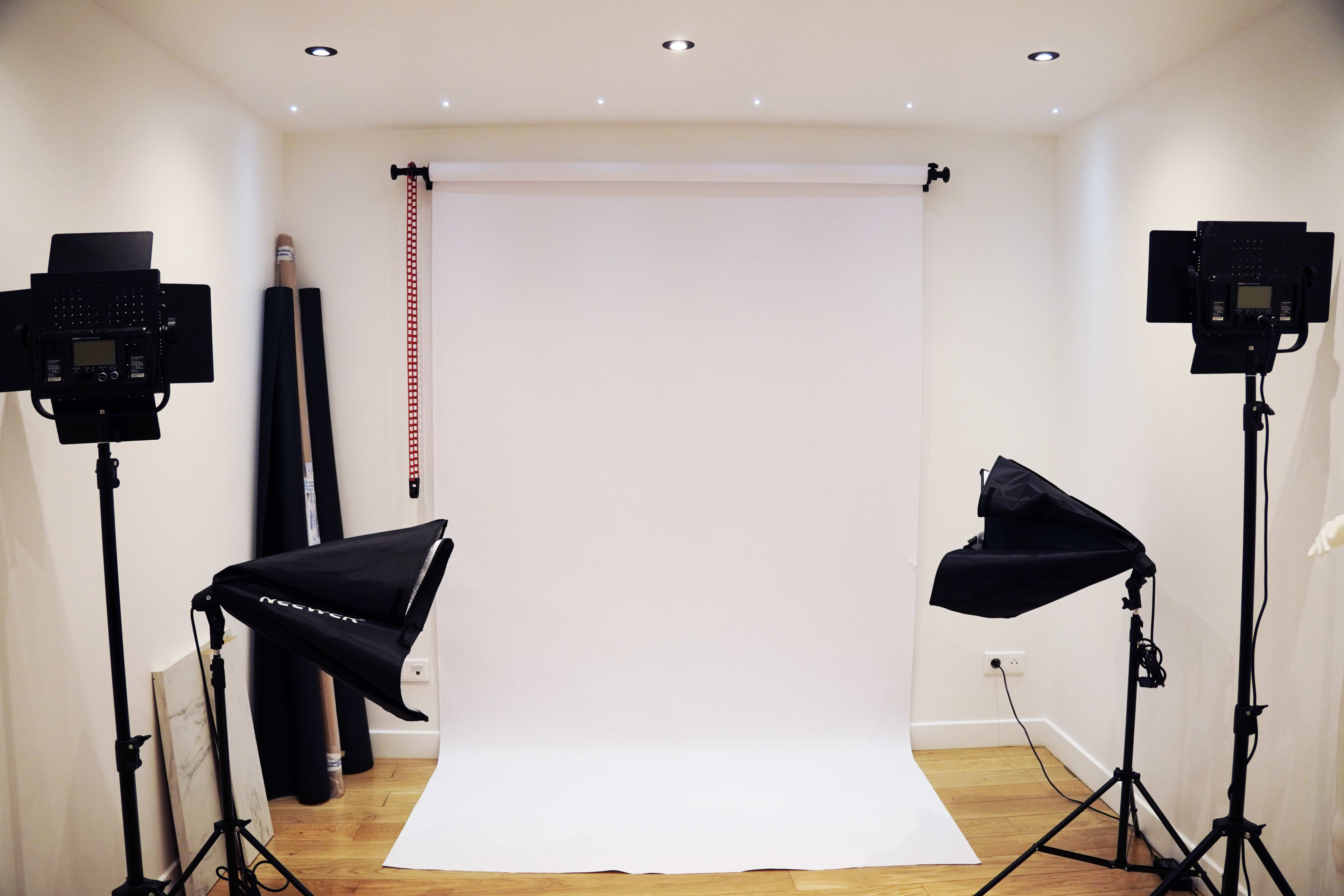 A photography studio setup with a white backdrop and two lighting stands on either side.