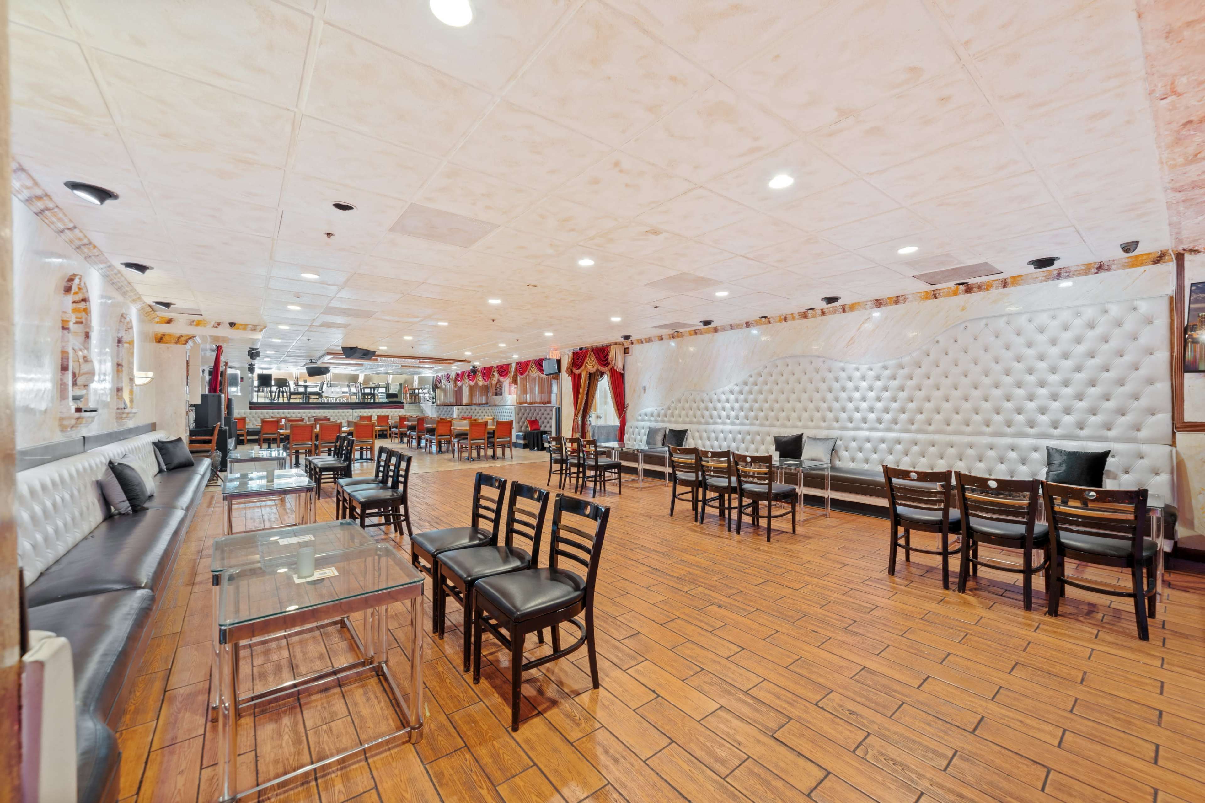 A spacious restaurant interior with leather seating, wooden flooring, and a partially visible kitchen area in the background.