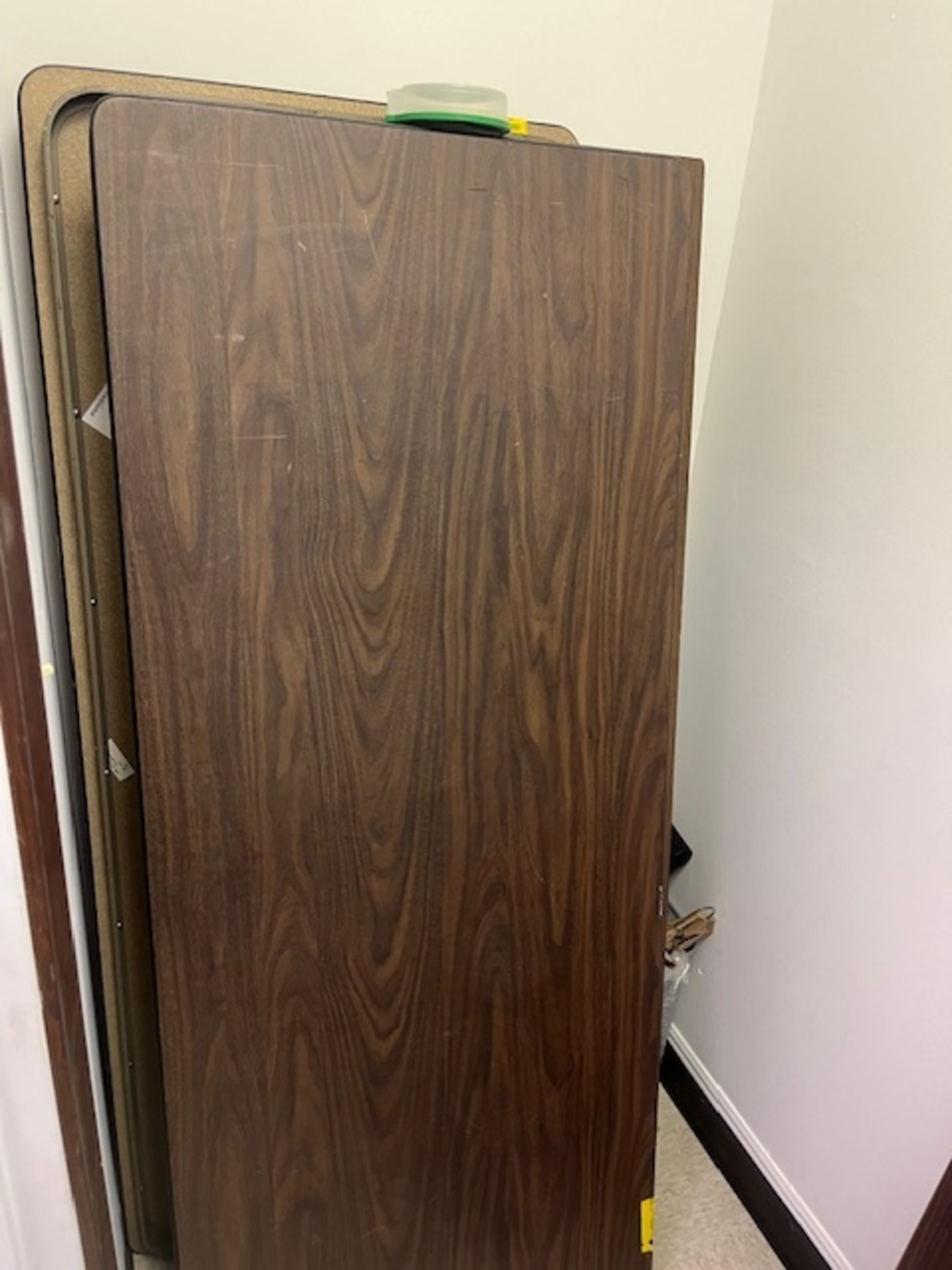 A wooden folding table is propped against a wall in a small room.