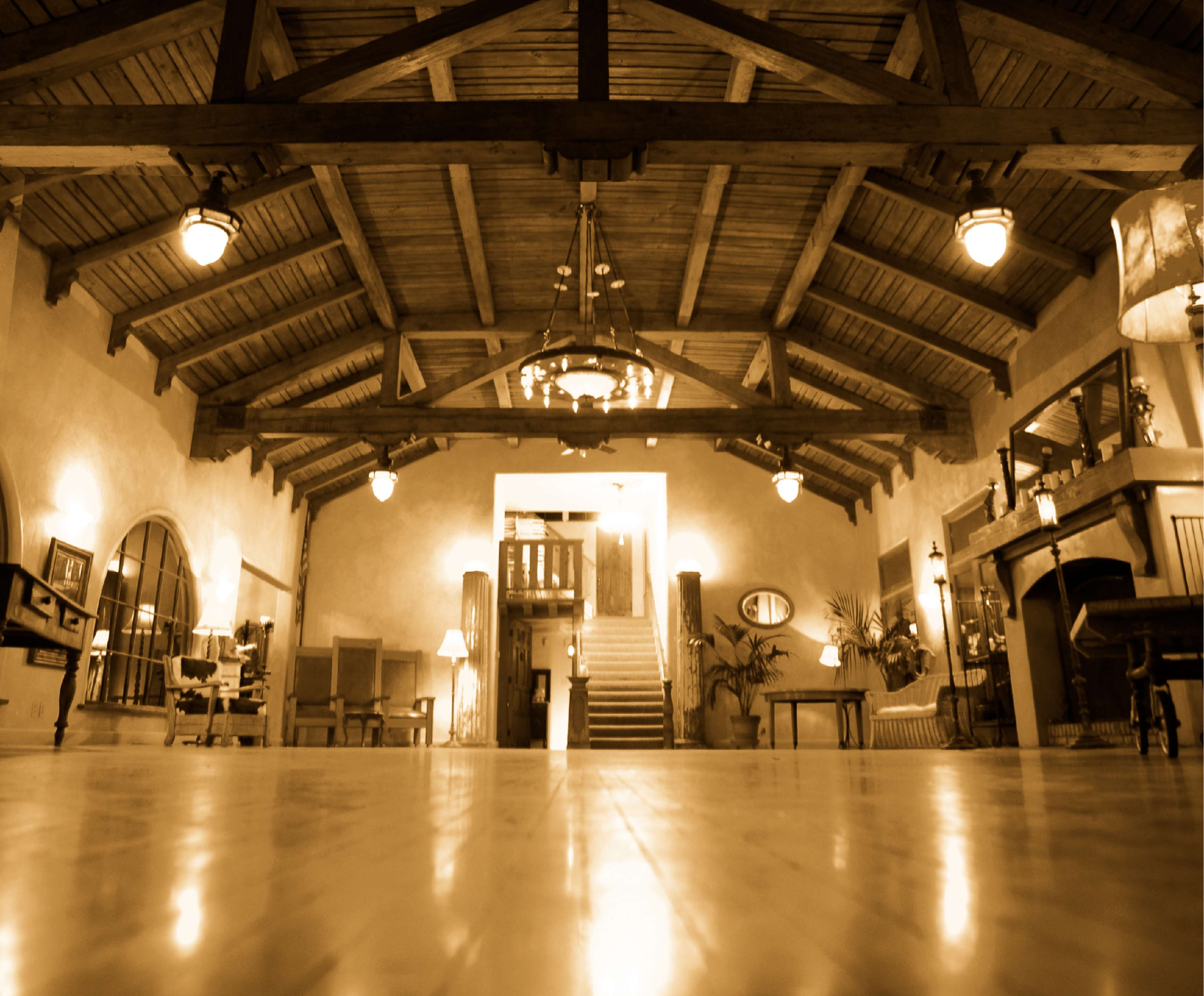 A spacious interior of a lobby with wooden beams, elegant lighting, and decorative furniture.