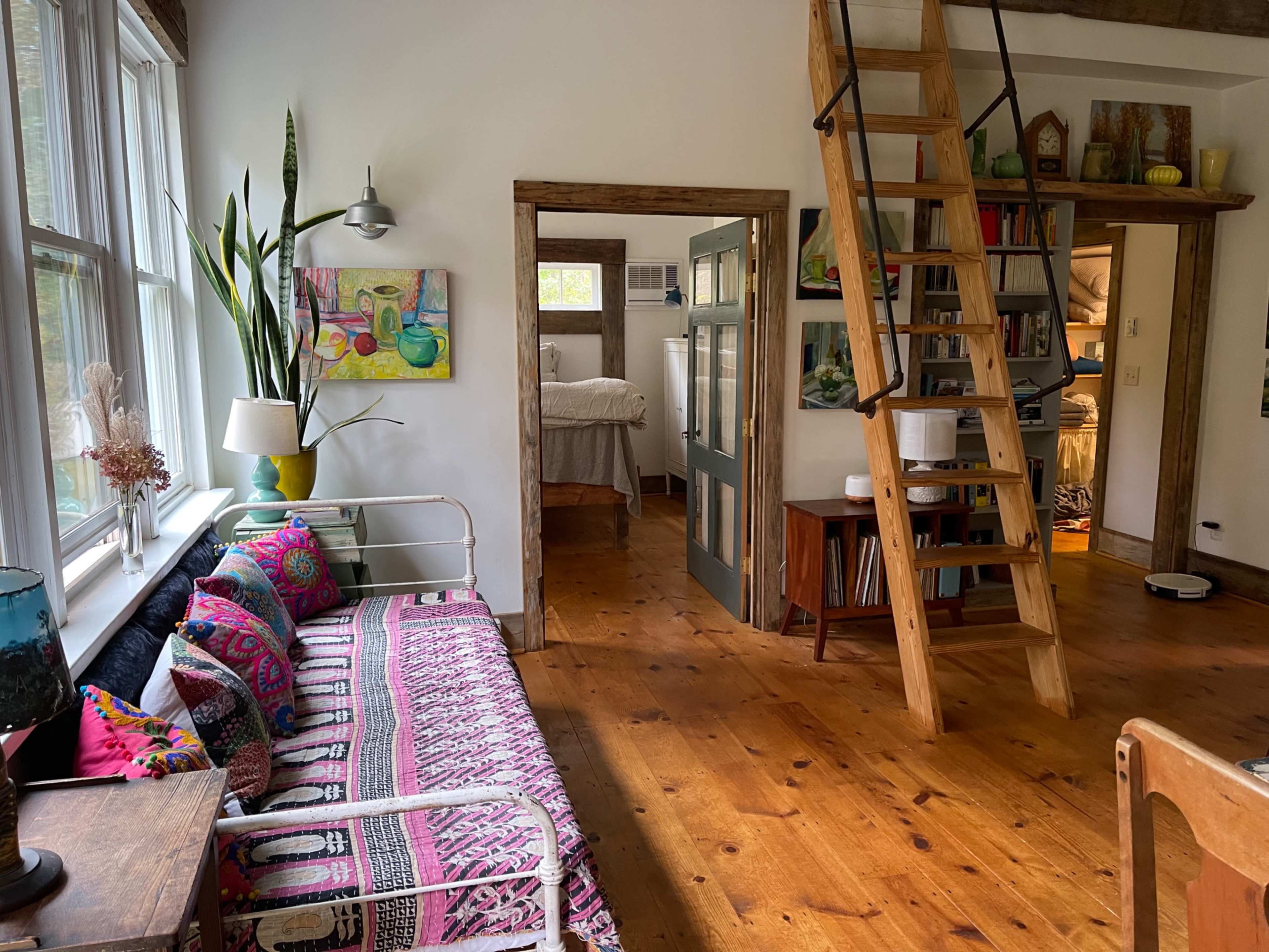 A cozy interior space with a colorful couch, a wooden floor, and a staircase leading to an upper level.