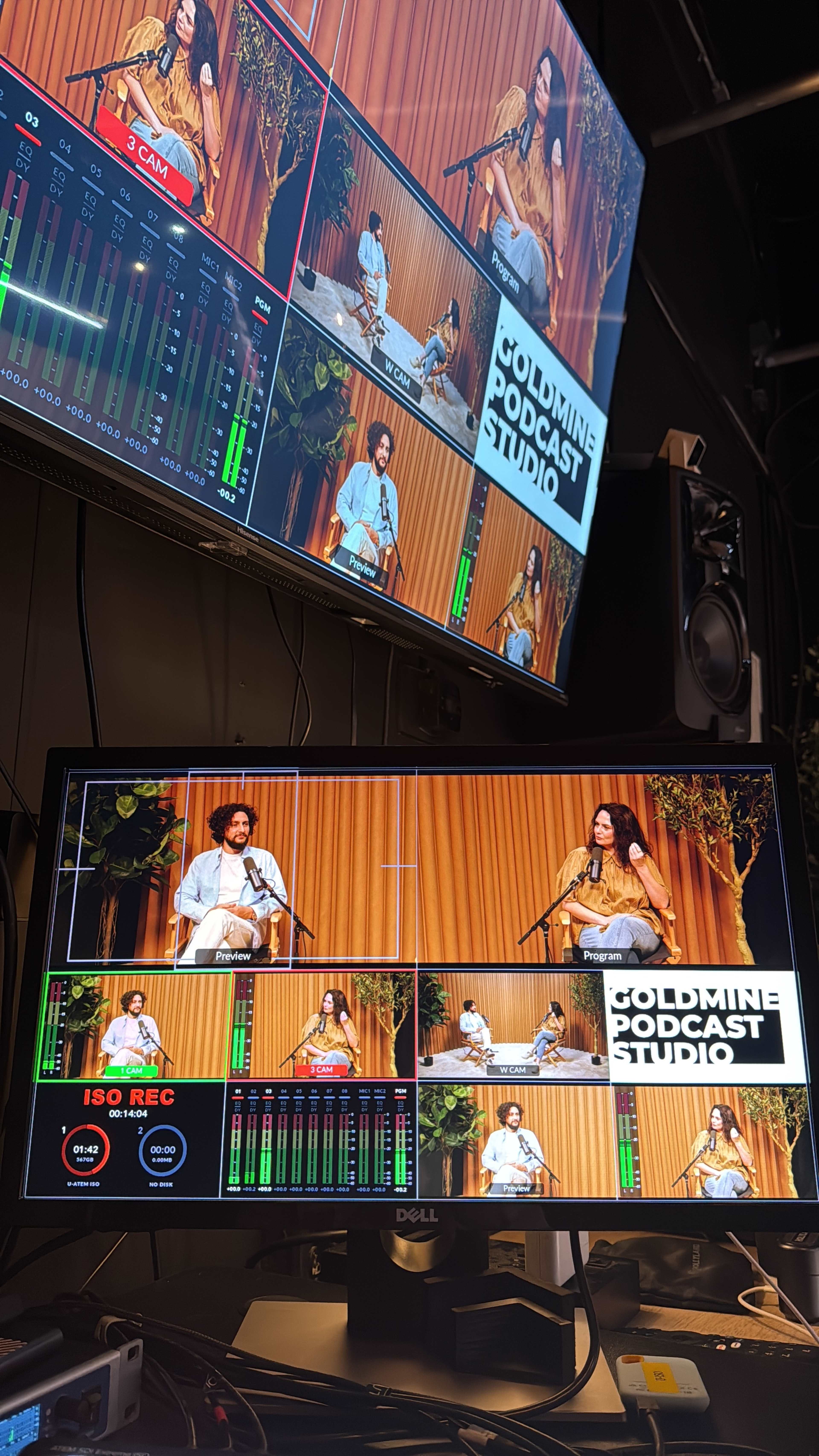 The image shows a multi-screen setup displaying a podcast studio with a host and guest in front of a wood-paneled backdrop.