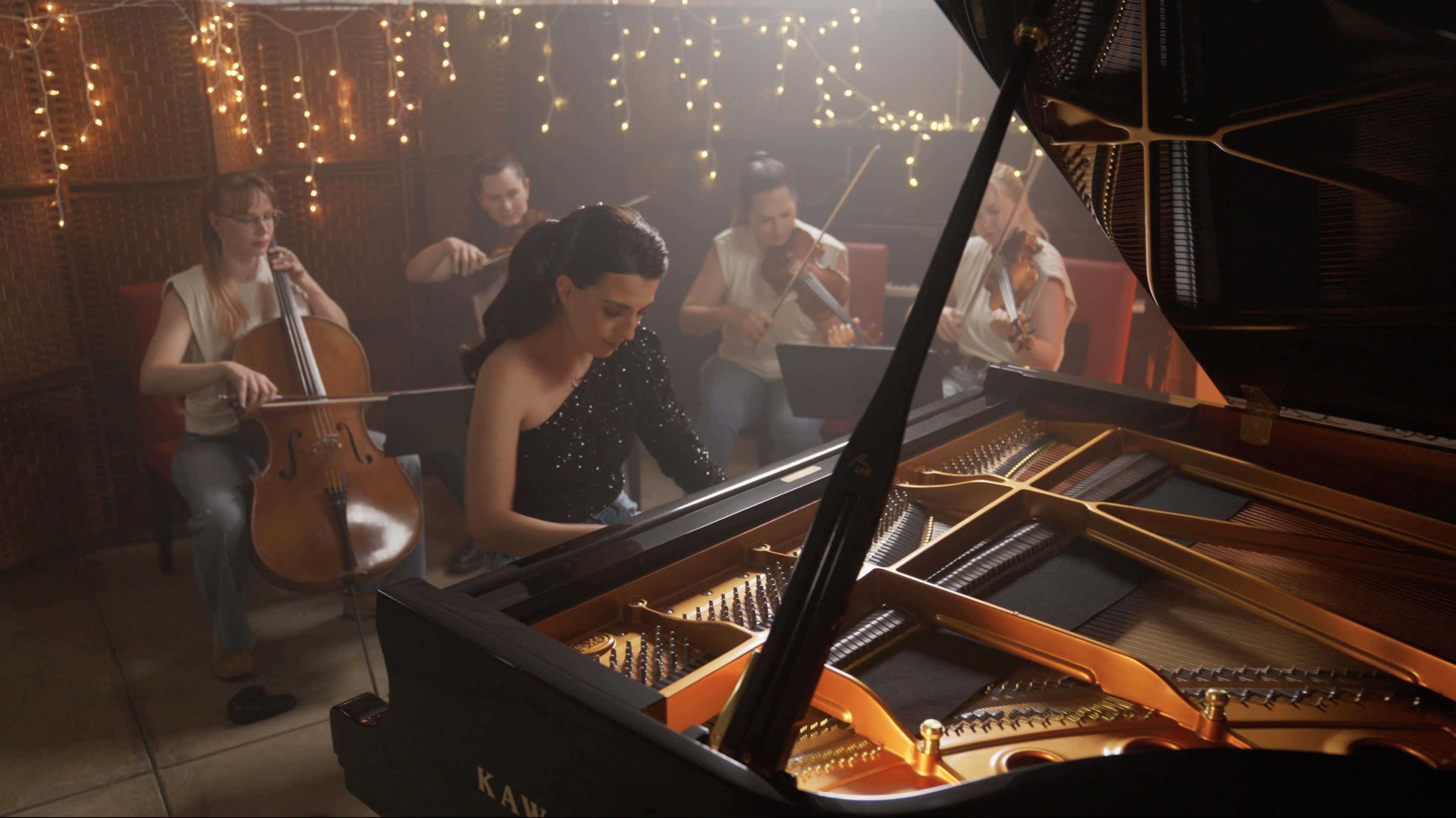 A pianist performs at a dimly lit venue, accompanied by string musicians in the background.