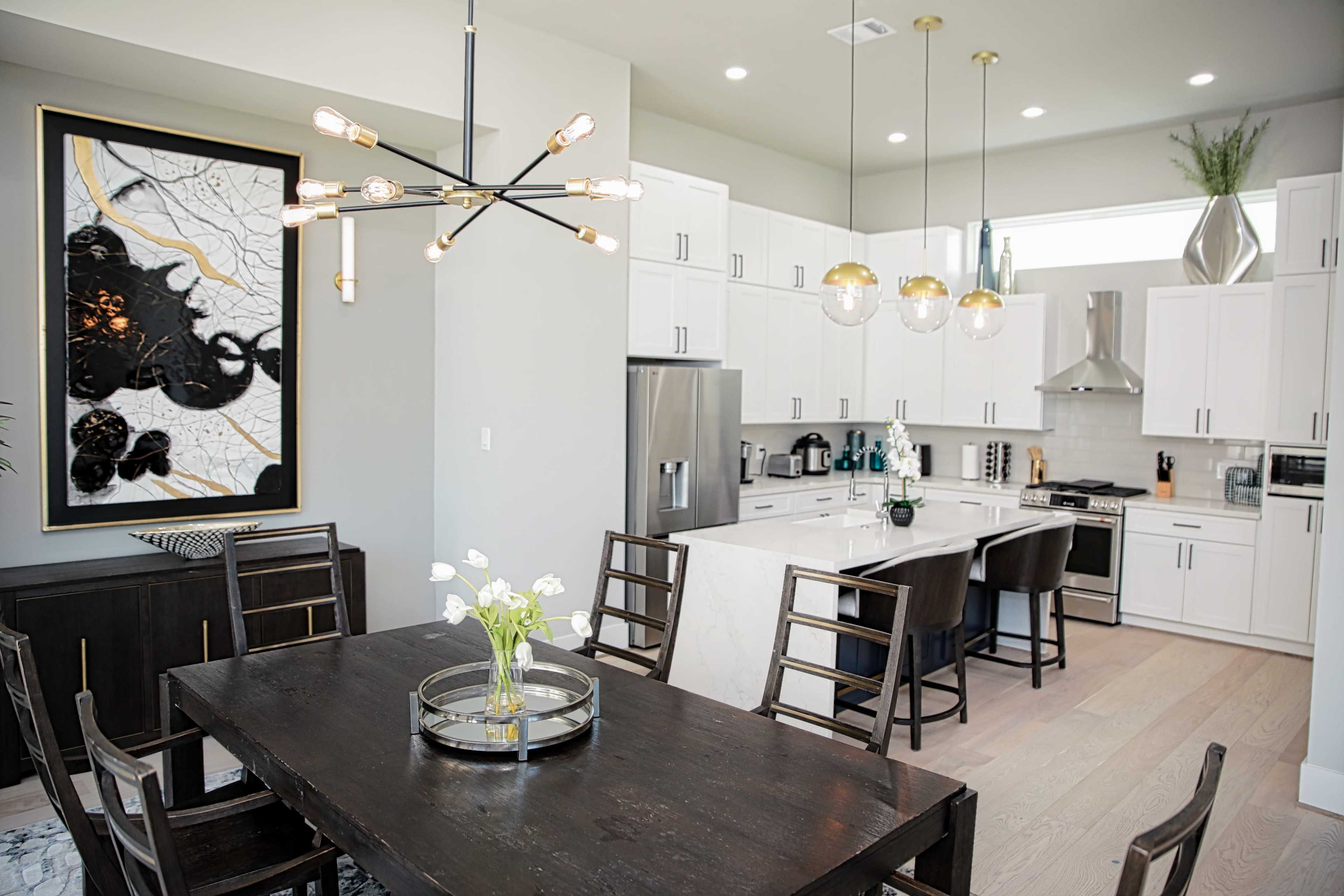 The image shows a modern kitchen and dining area with white cabinetry, a central island, and a dining table set for six.