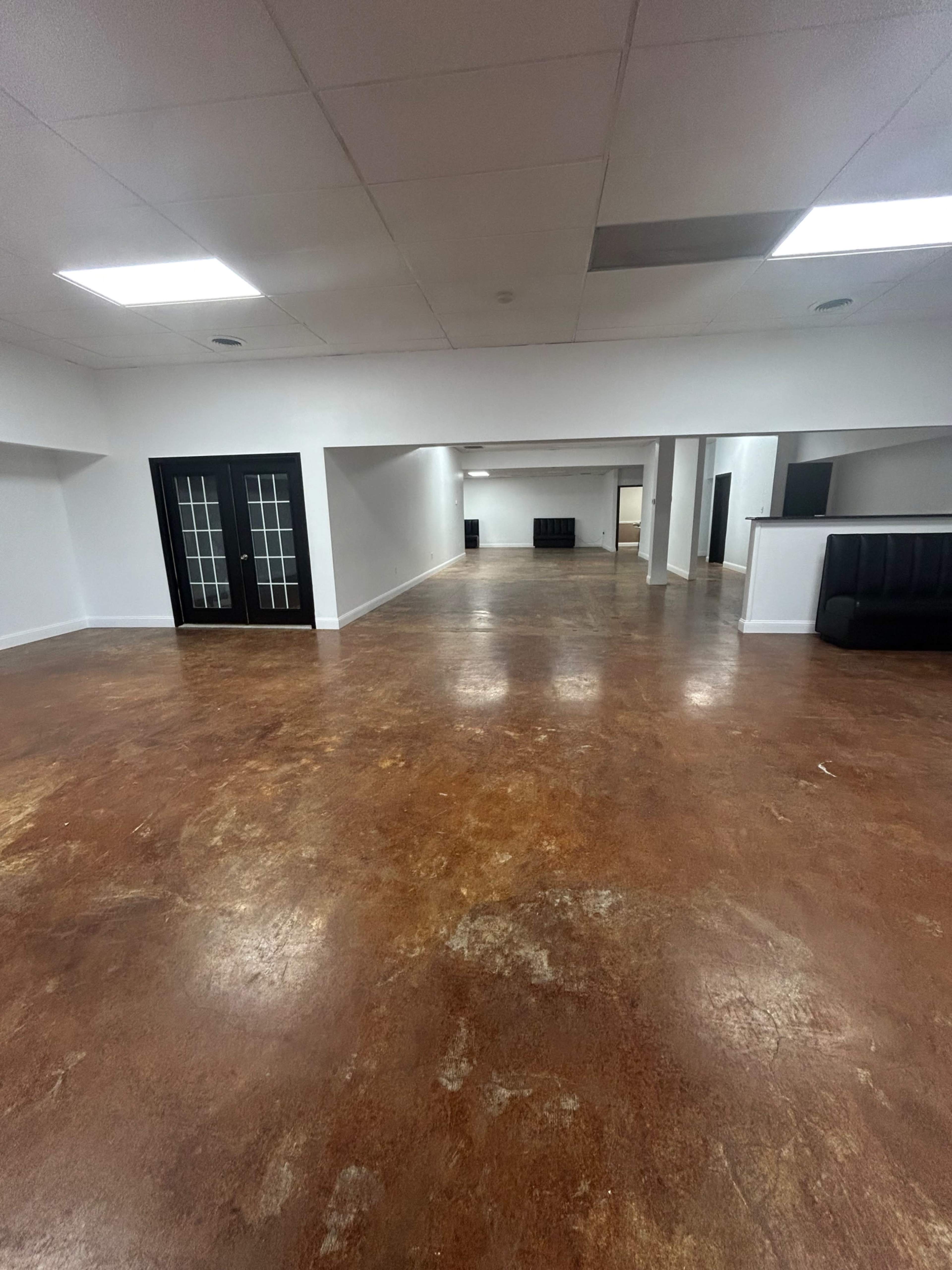 The image shows a spacious, empty interior room with a polished concrete floor and several dividing walls.