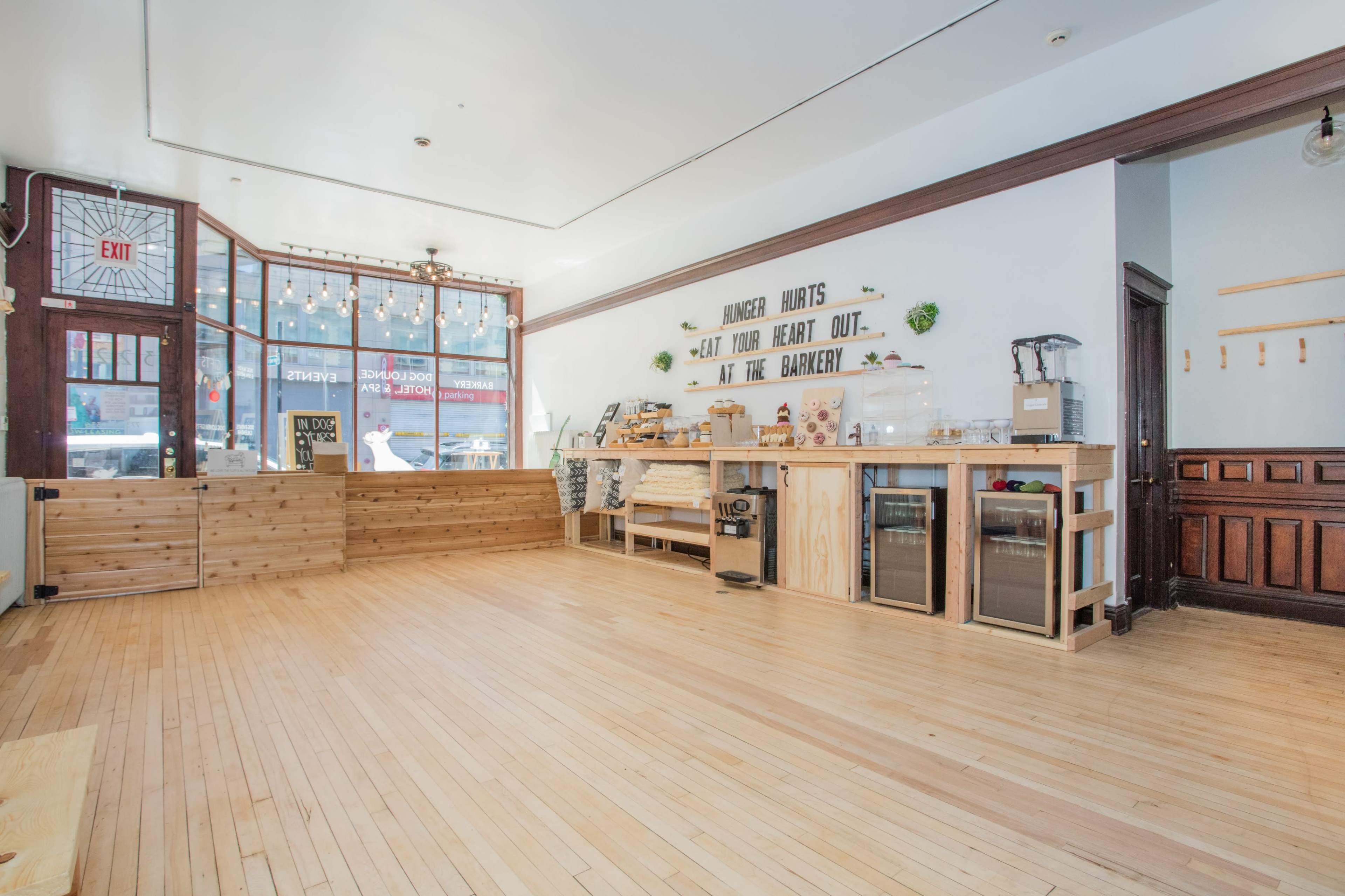 A spacious, minimally decorated cafe with wooden flooring and a counter made of light-colored wood.