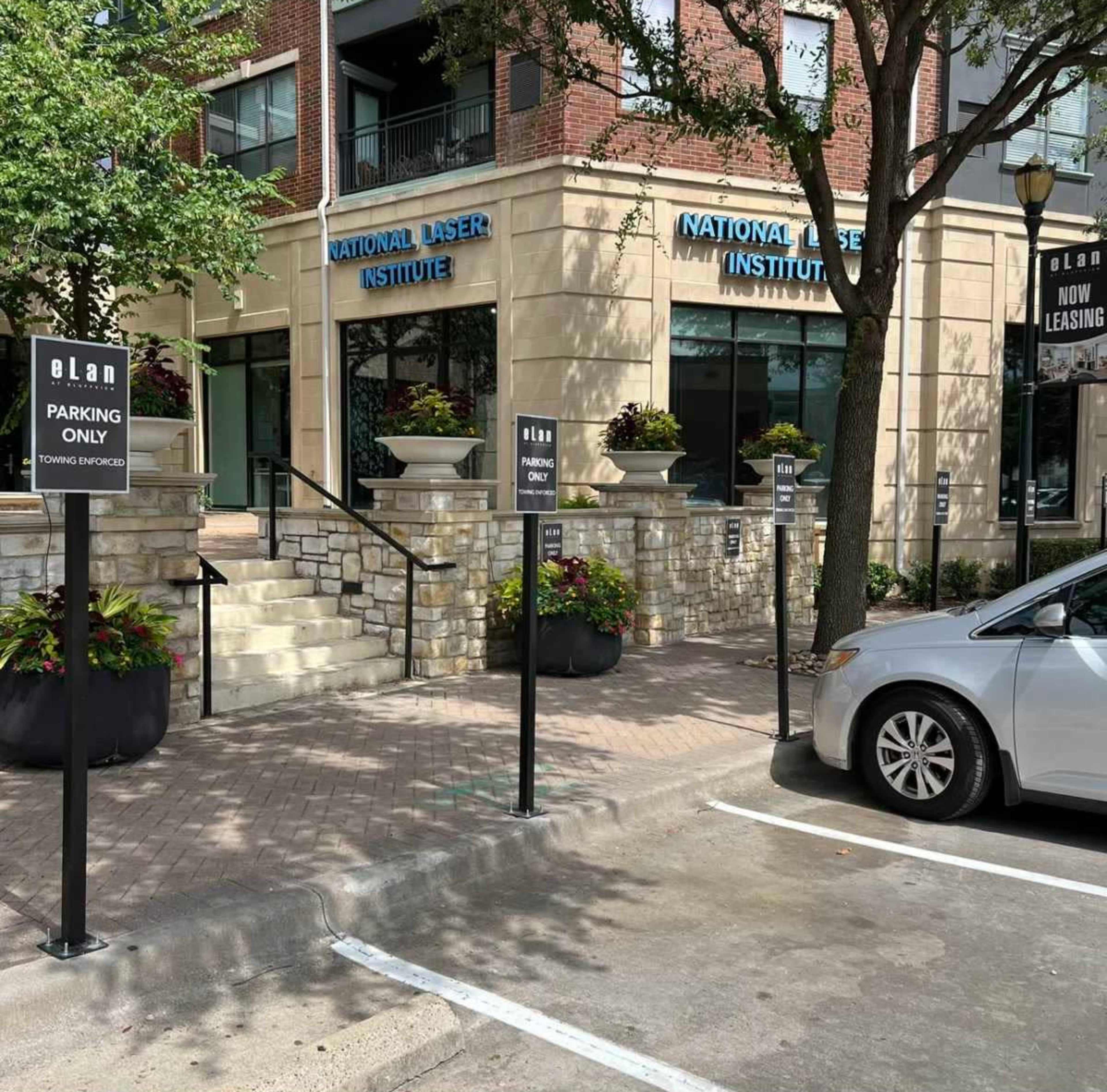 The image shows a parking area in front of a building with signs indicating "Parking Only" and "Tow Away Zone."