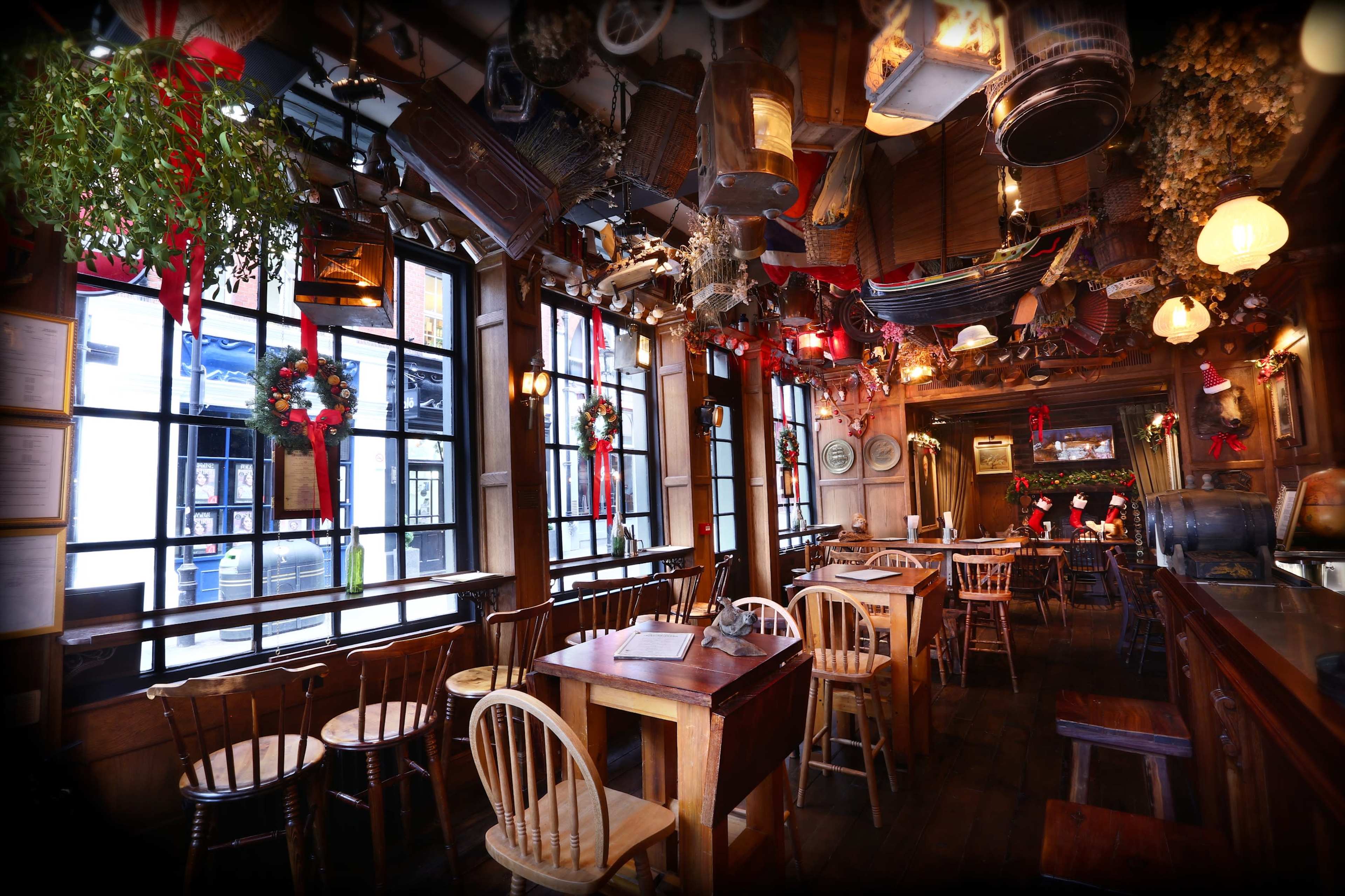 The image shows a rustic restaurant interior adorned with decorations, including wreaths and various hanging objects, illuminated by warm lighting.