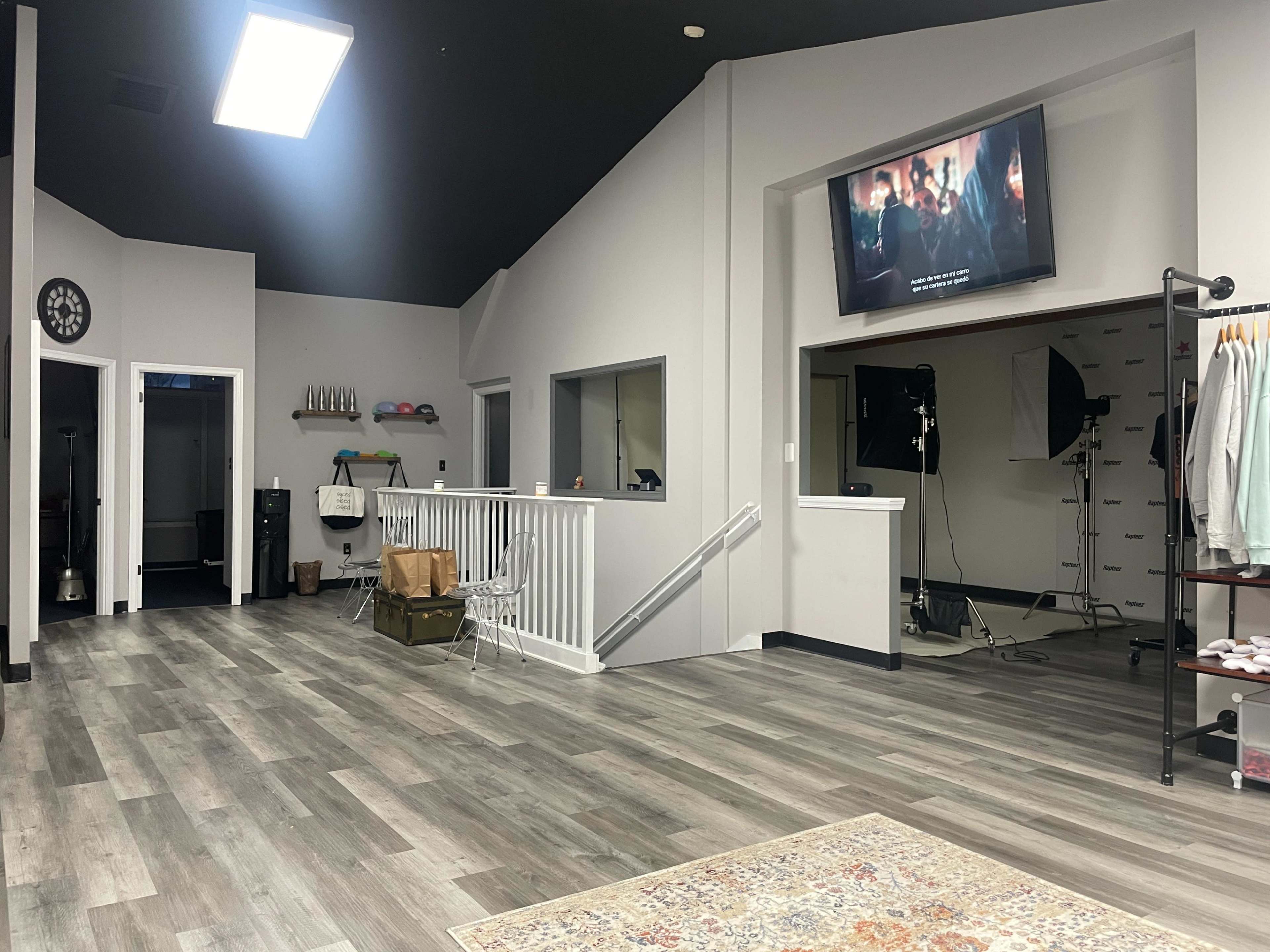 A spacious, modern interior room with a television mounted on the wall, large windows, and a variety of equipment arranged in a corner.