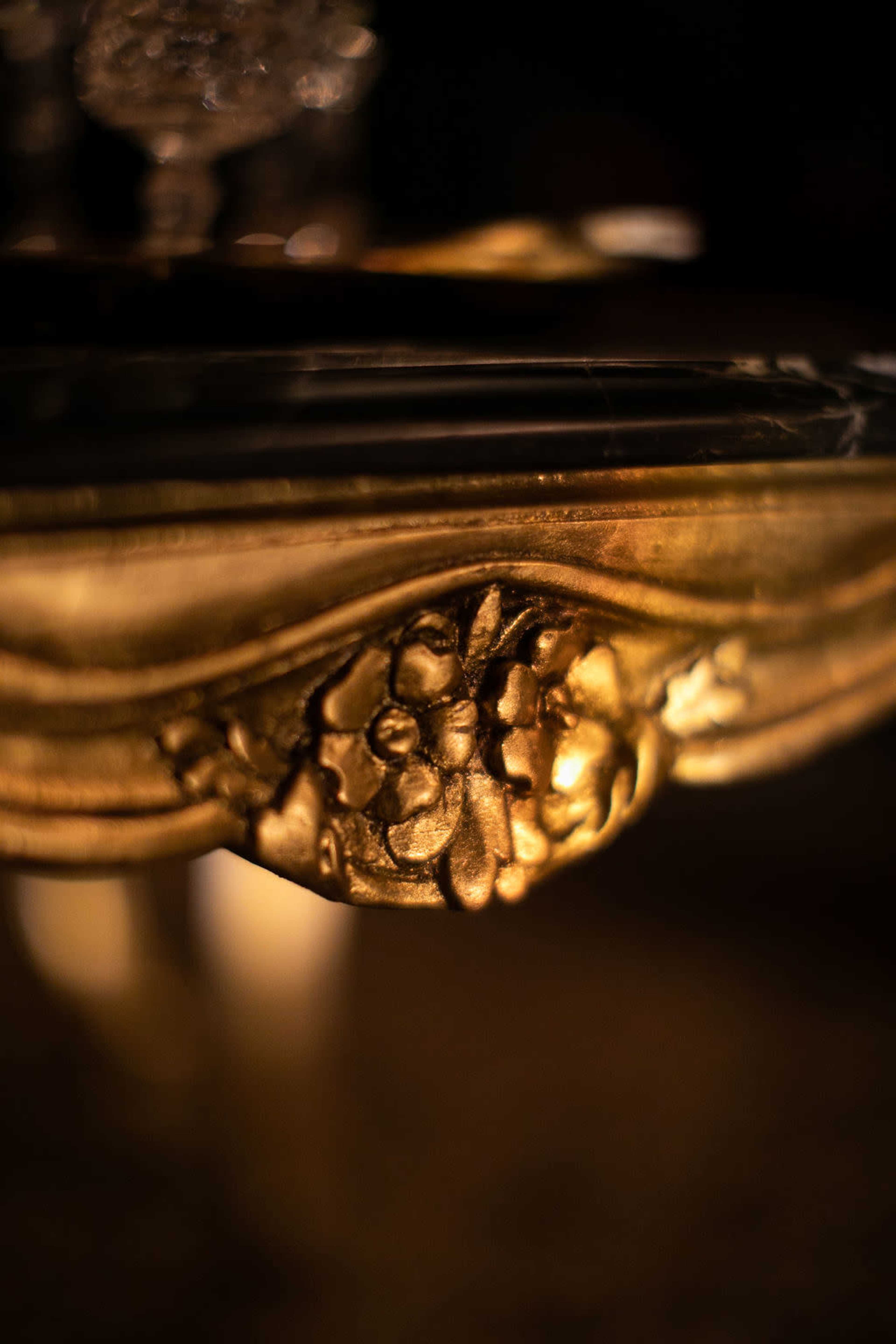 The image features a close-up of an ornate, gold-colored decorative element with floral motifs on a dark background.