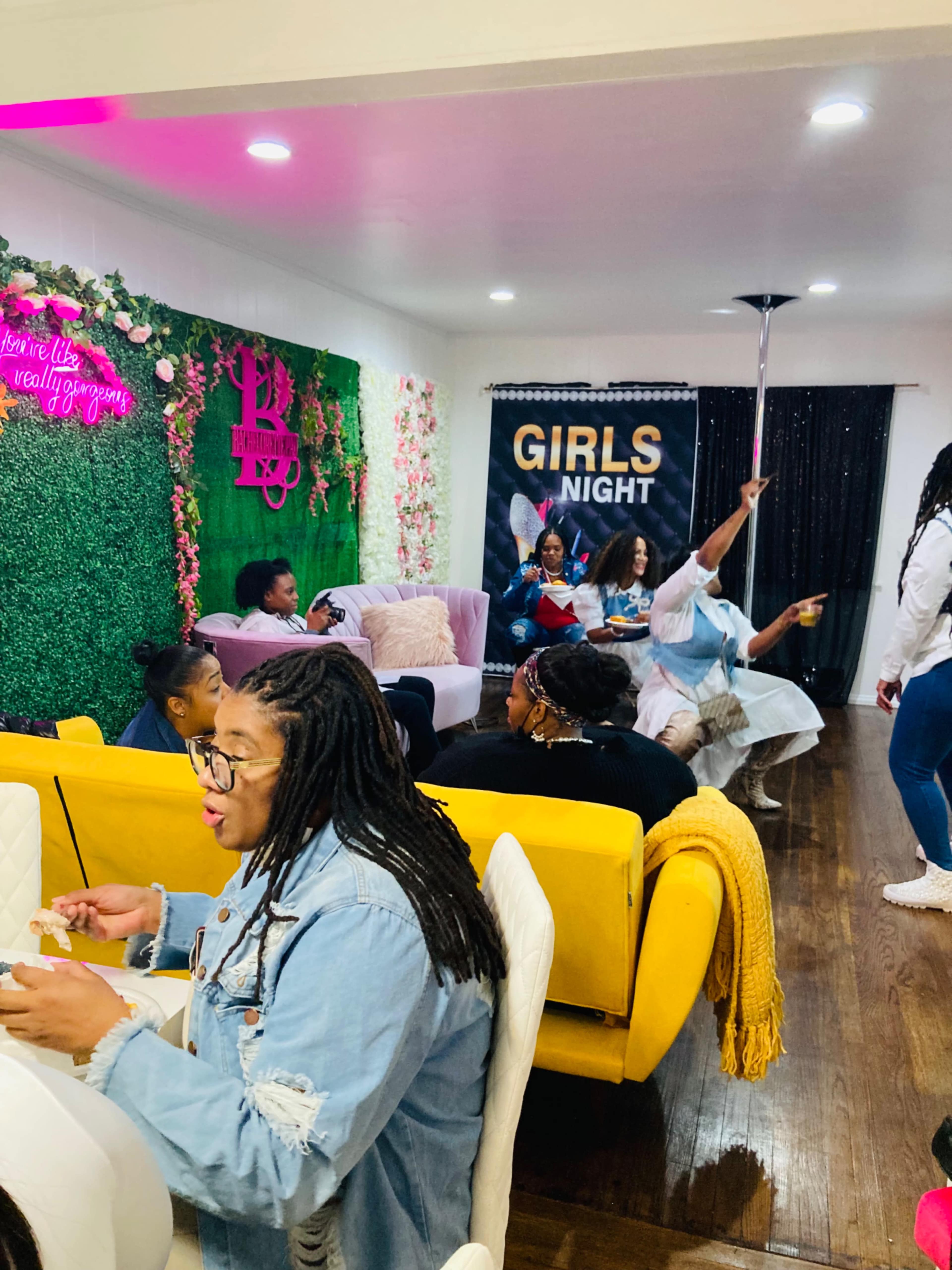 A lively indoor gathering where a group of women is enjoying a "Girls Night" event, with seating arrangements featuring colorful couches and wall decorations.