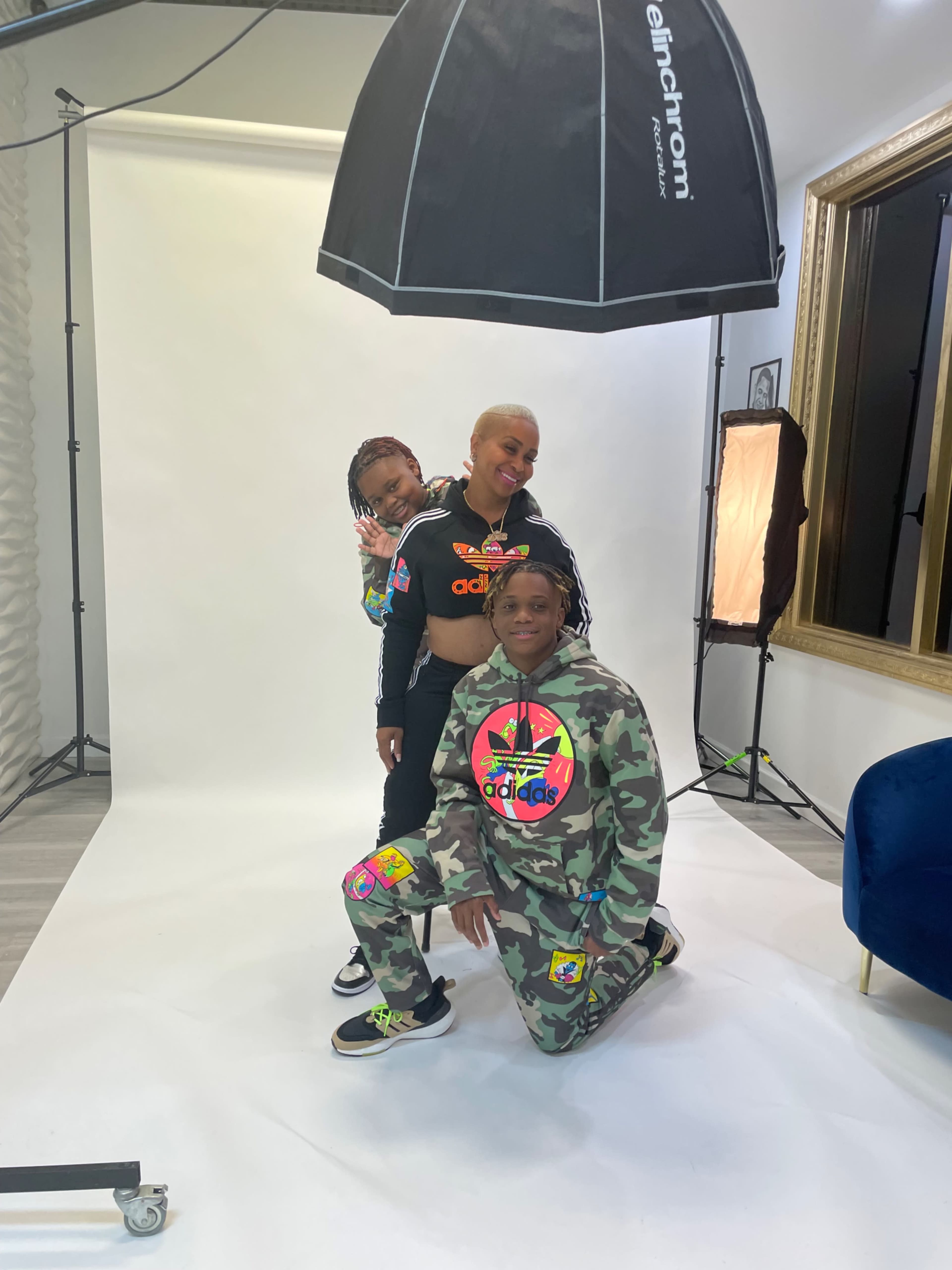 Three individuals pose together in a studio setting, wearing colorful athletic clothing, with photography equipment in the background.