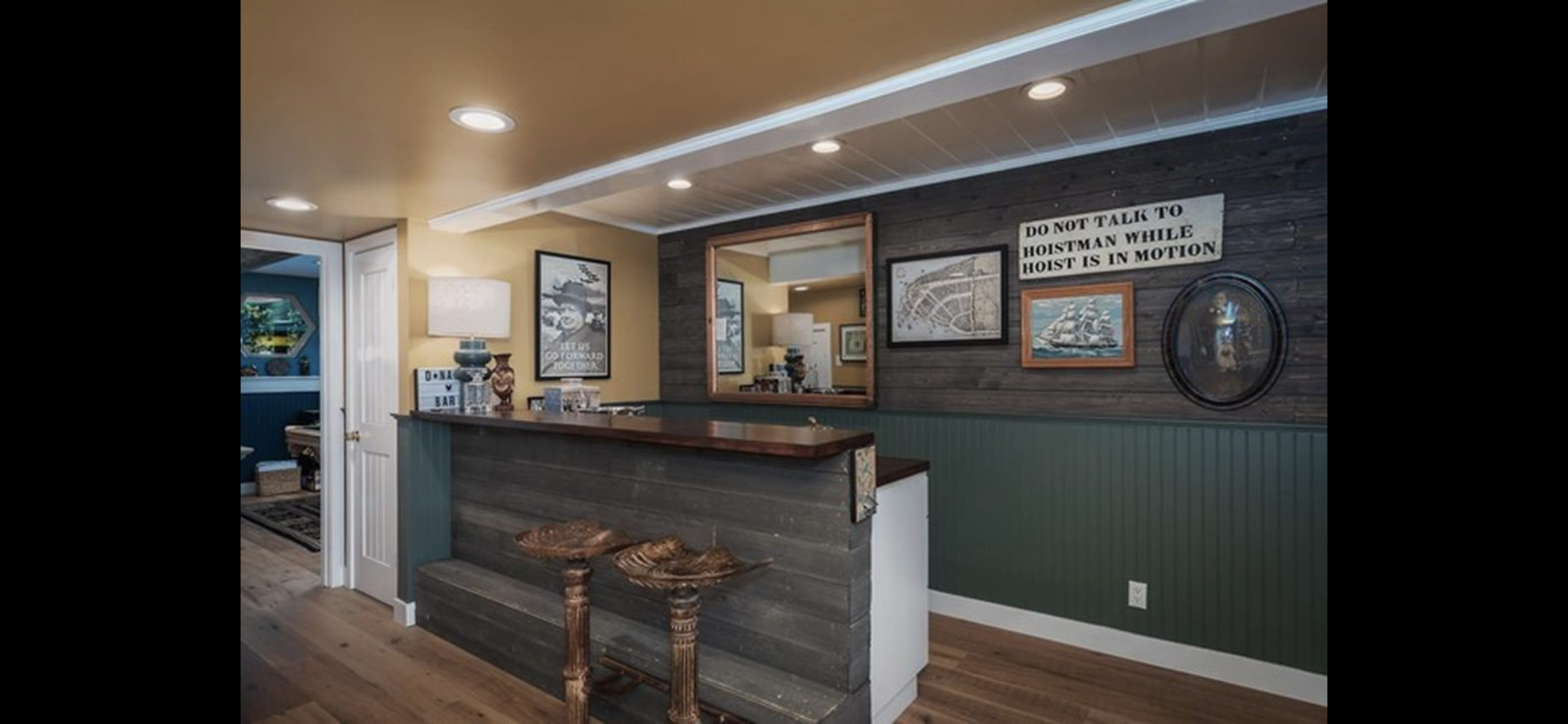 A small, rustic bar area features wooden accents, framed artwork on the walls, and a mirror above the counter.