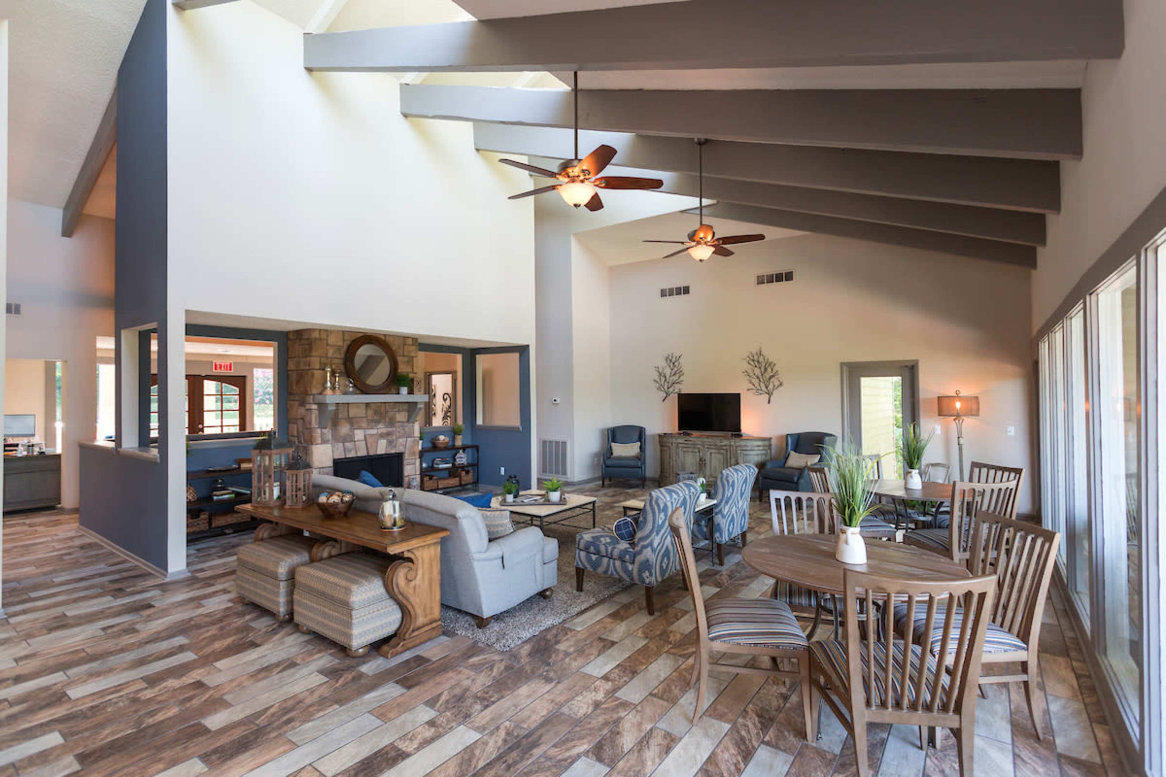 The spacious living area features high ceilings, wooden beams, and a combination of seating arrangements with a table set for dining.
