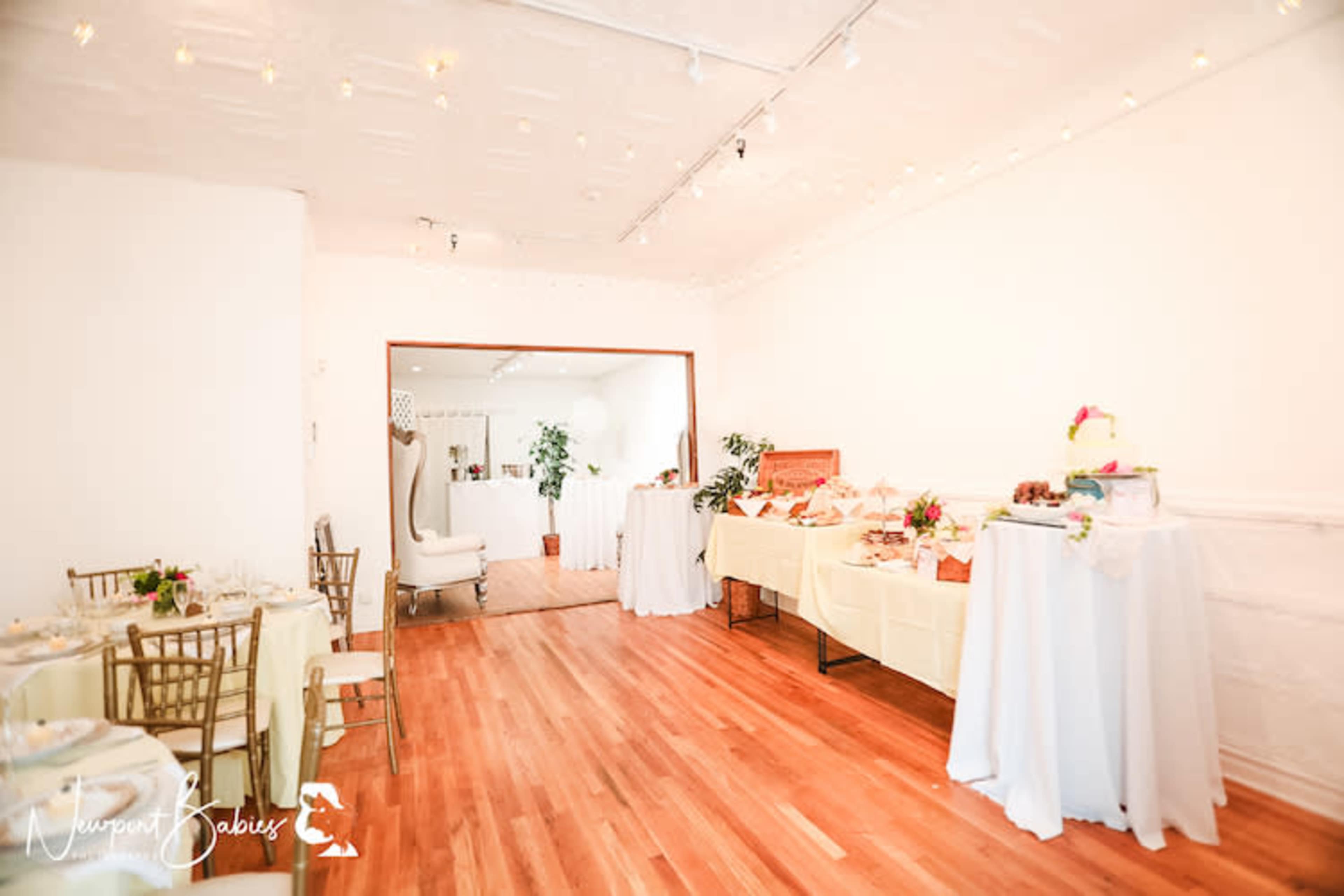 A well-decorated room with tables set up for a dining event, featuring food displays and floral arrangements.