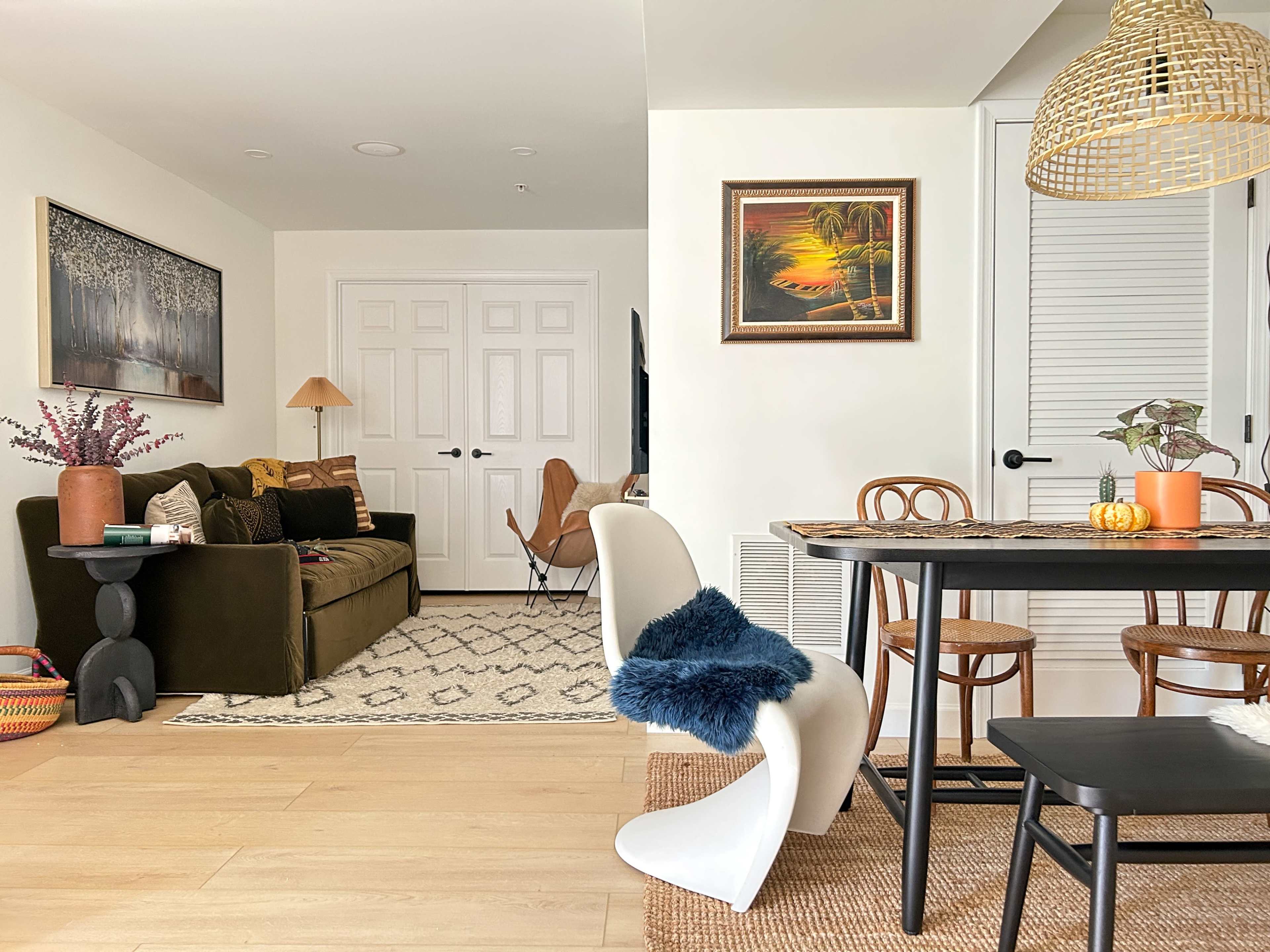 A modern living room and dining area featuring a sofa, a dining table with chairs, and decorative artwork on the walls.