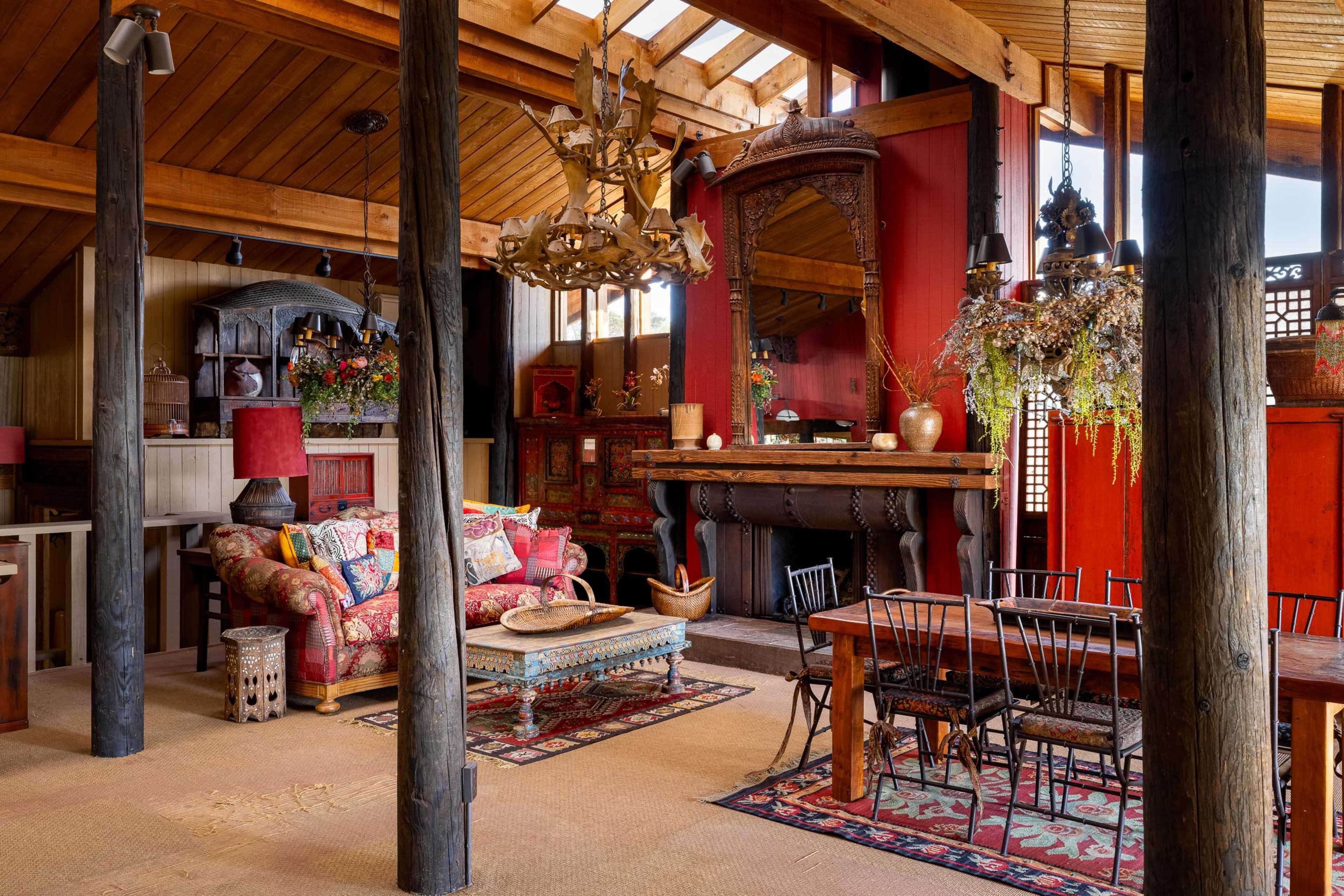 The image shows a cozy living space with a mix of colorful furnishings, wooden beams, and a dining area featuring a wooden table and chairs.