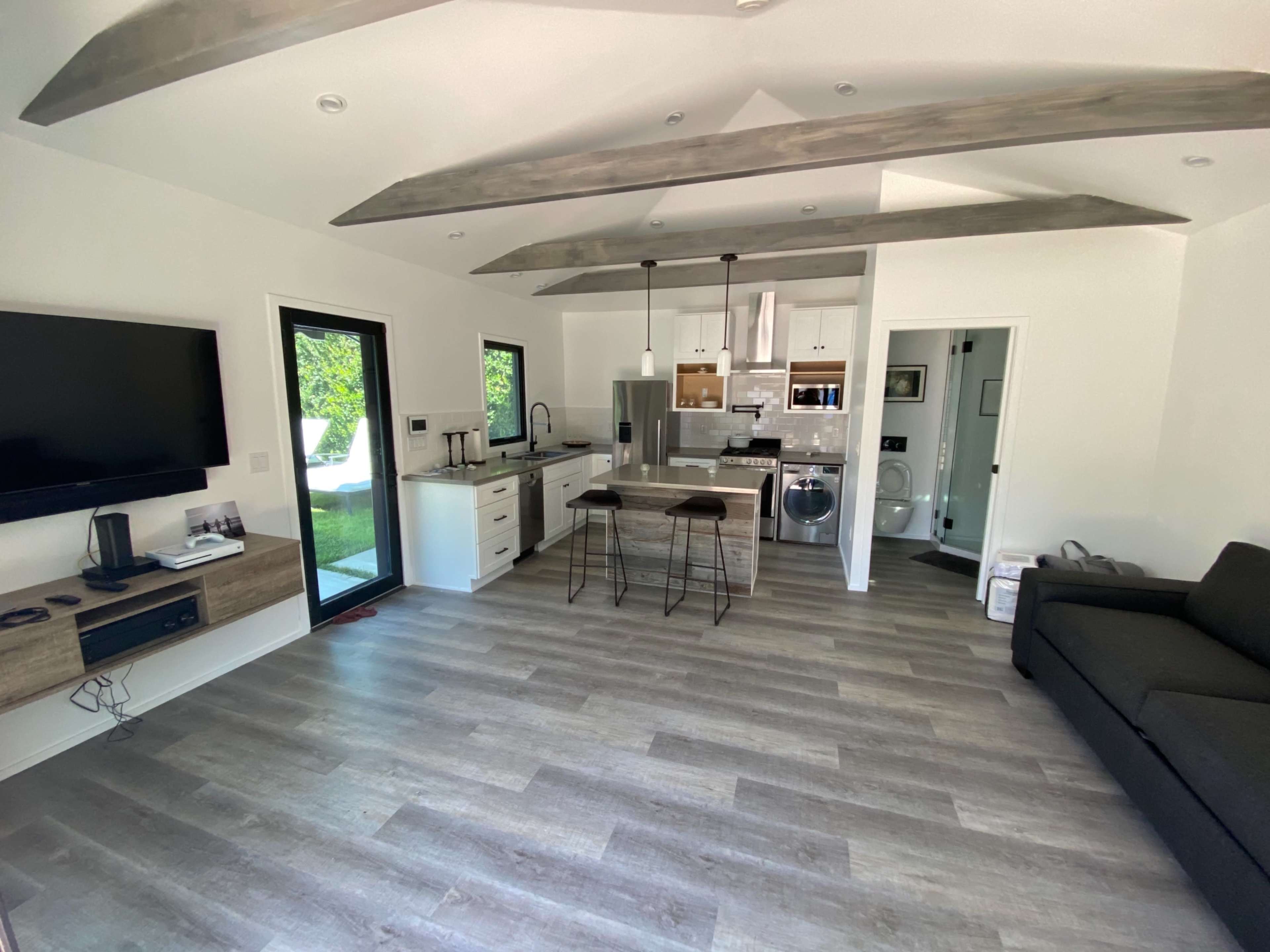 A modern, open-concept living space featuring a kitchen, dining area, and a living room with a sofa.