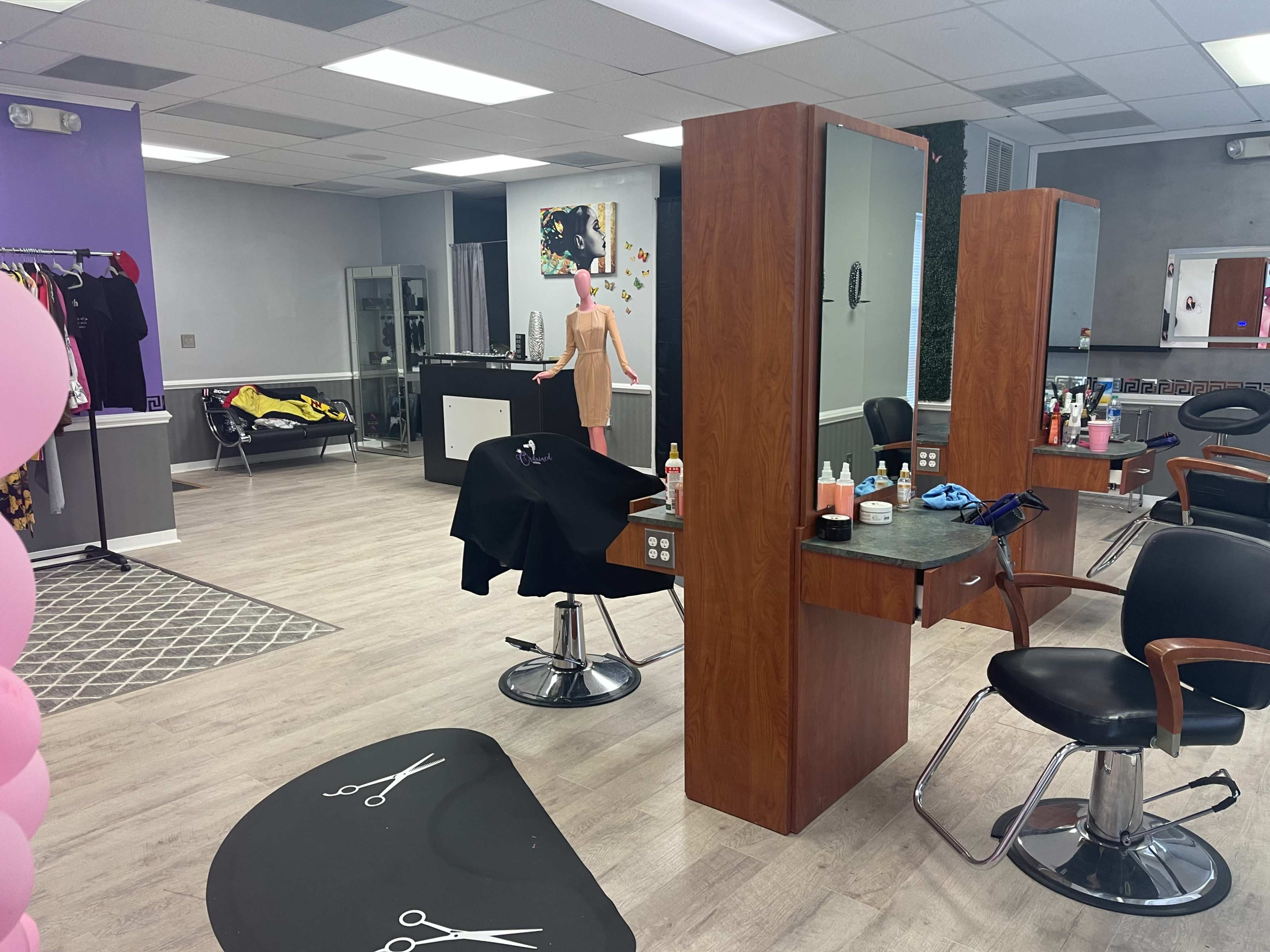 A hair salon with stylist stations, mirrors, and various hair products arranged on a counter.