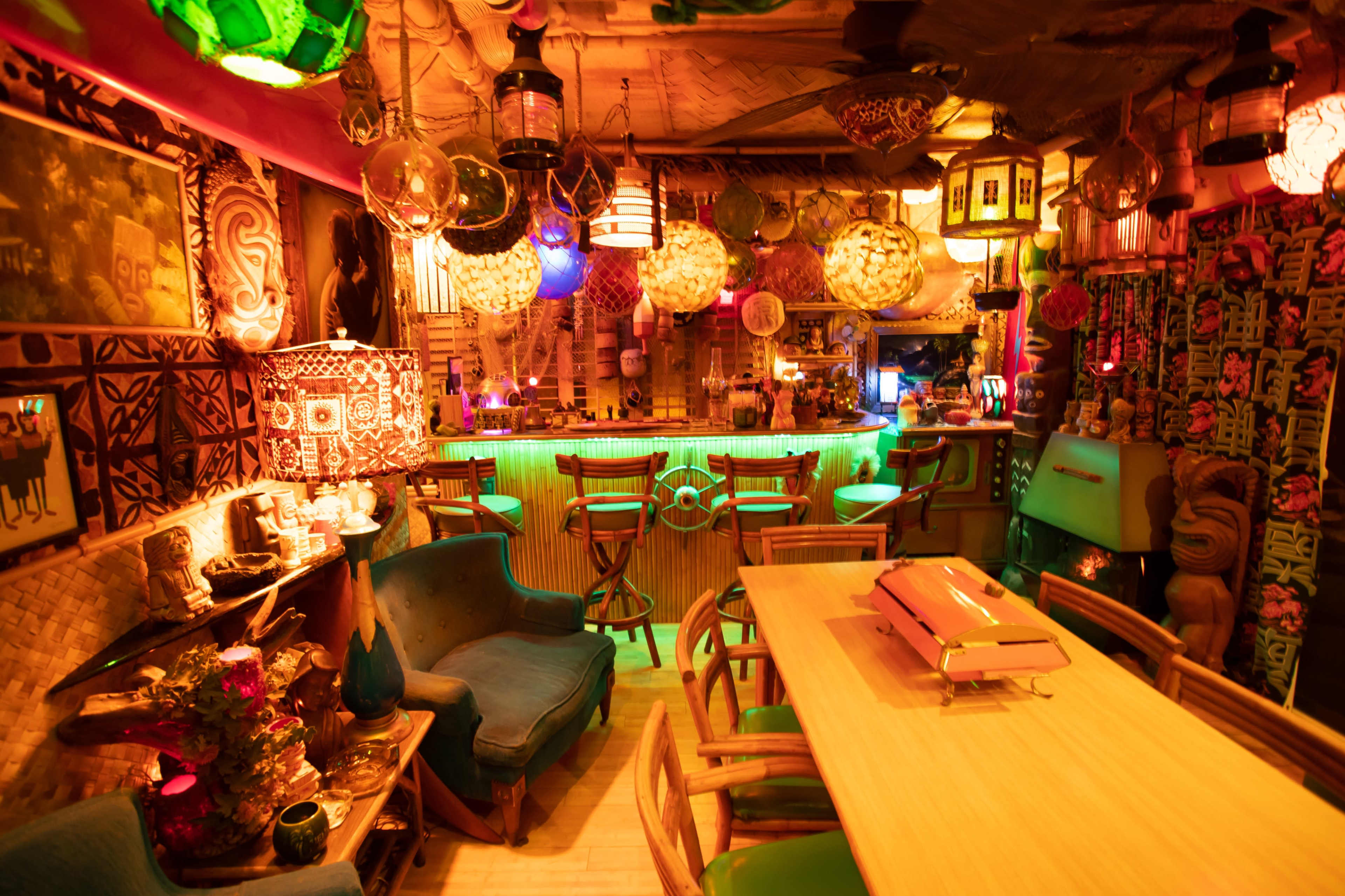 A vibrant tiki-themed bar with colorful lanterns, wooden decor, and cozy seating arrangements.