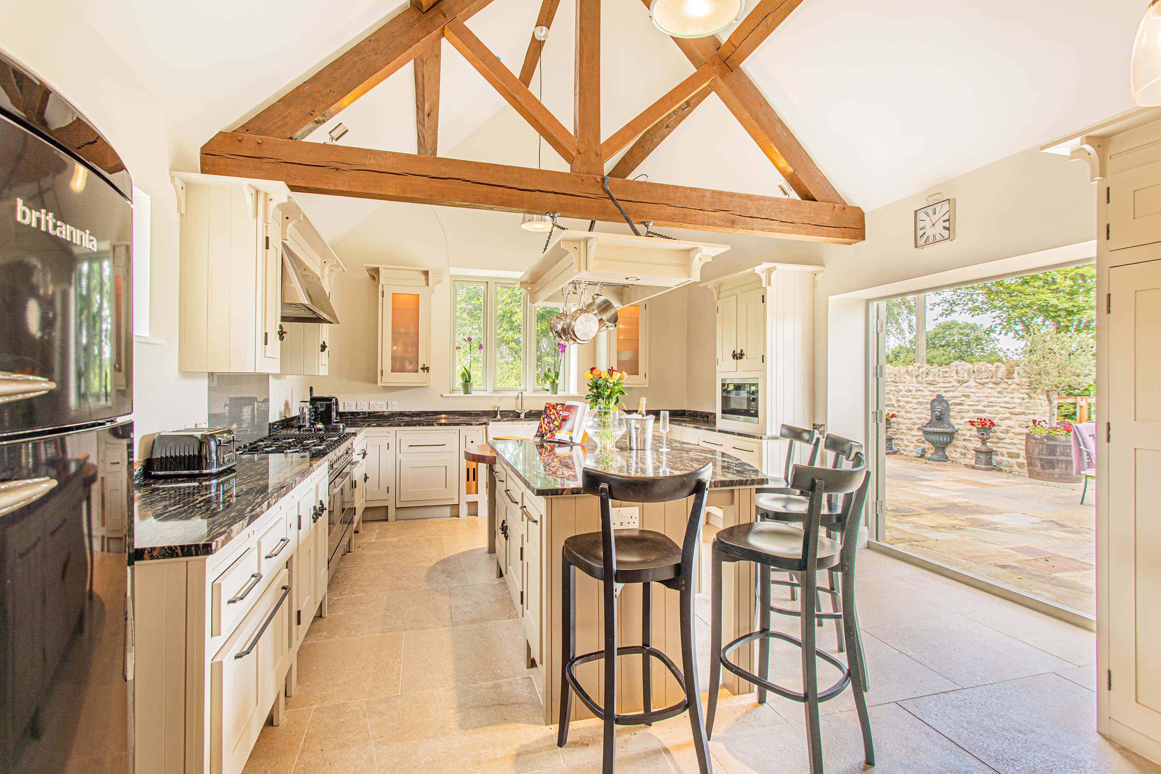 The kitchen features a spacious layout with a large island, wooden beams, and sliding glass doors that open to a patio.