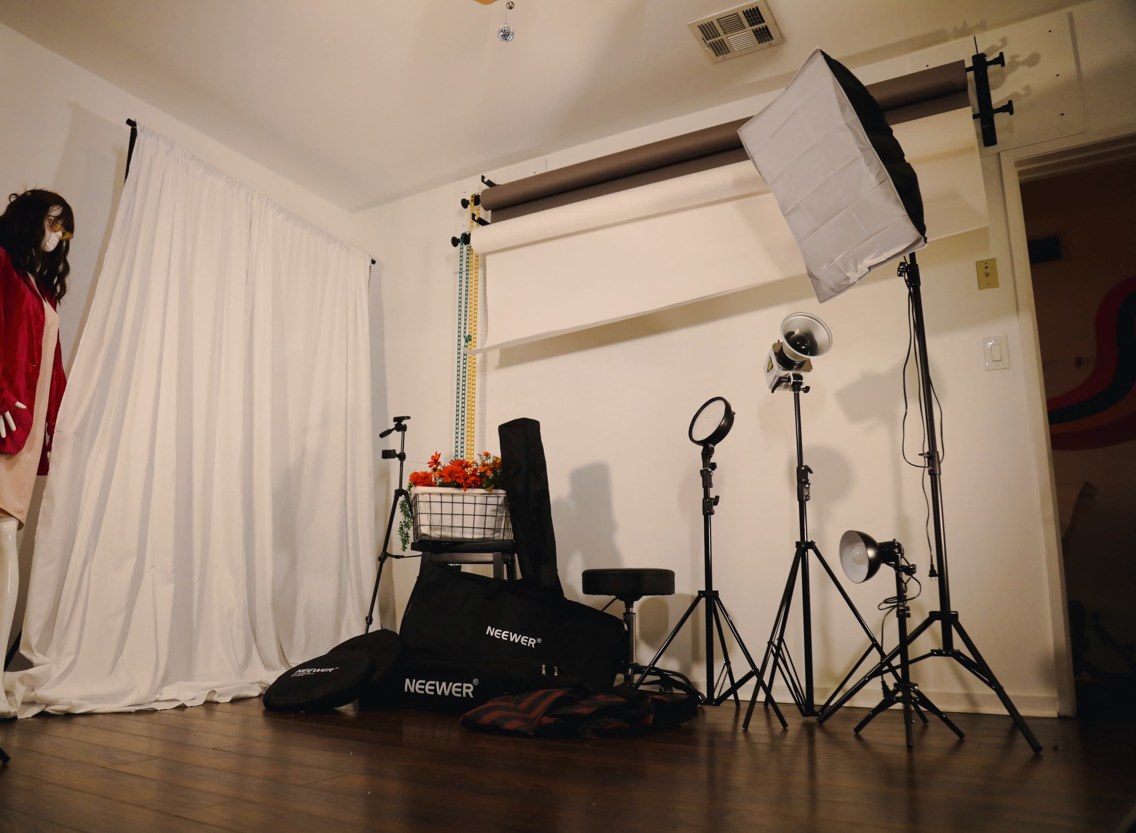 A photography studio setup with lighting equipment, softboxes, and a backdrop, along with a mannequin dressed in clothing.