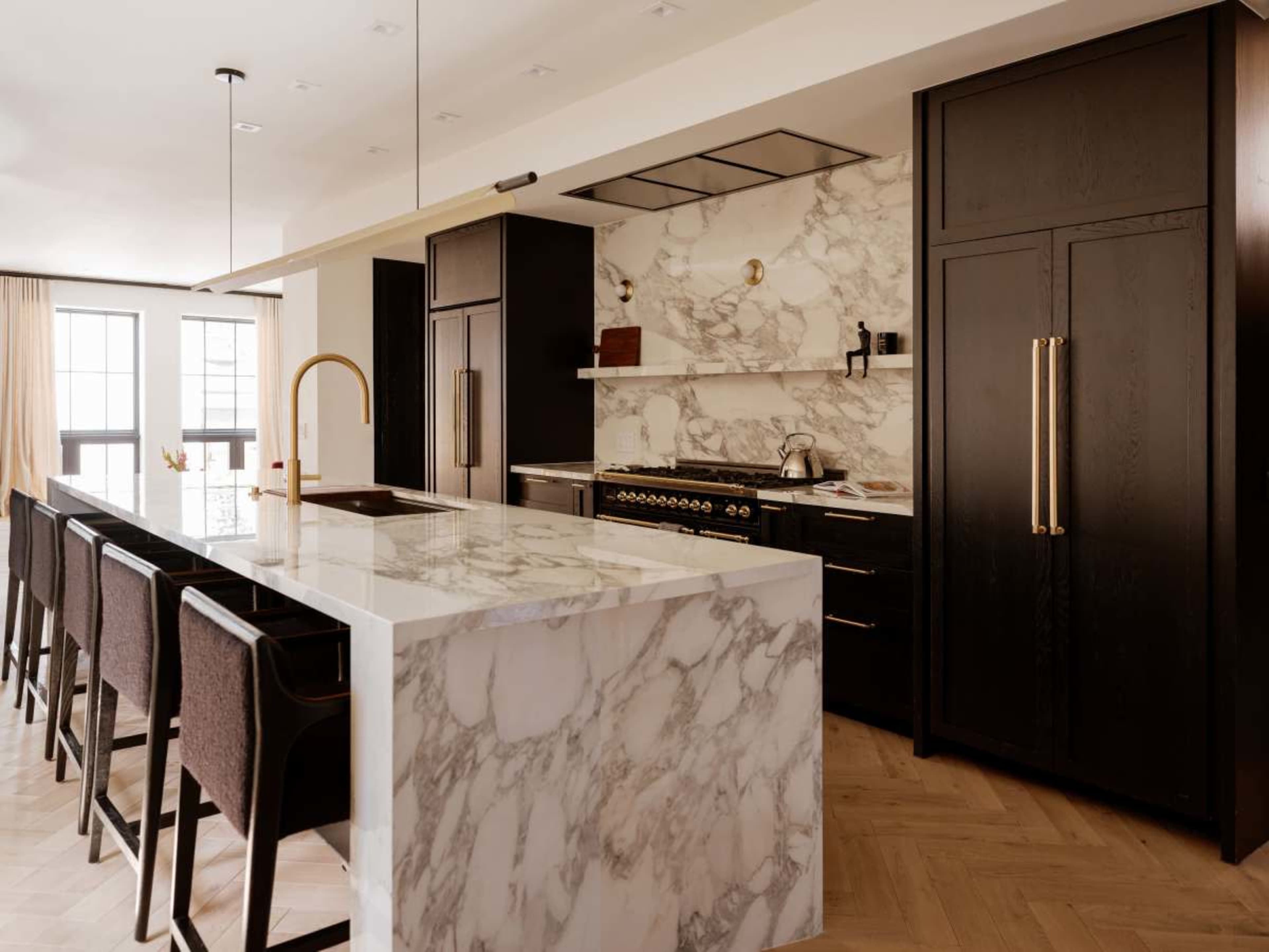 The kitchen features sleek black cabinetry and a large island with a marble countertop.