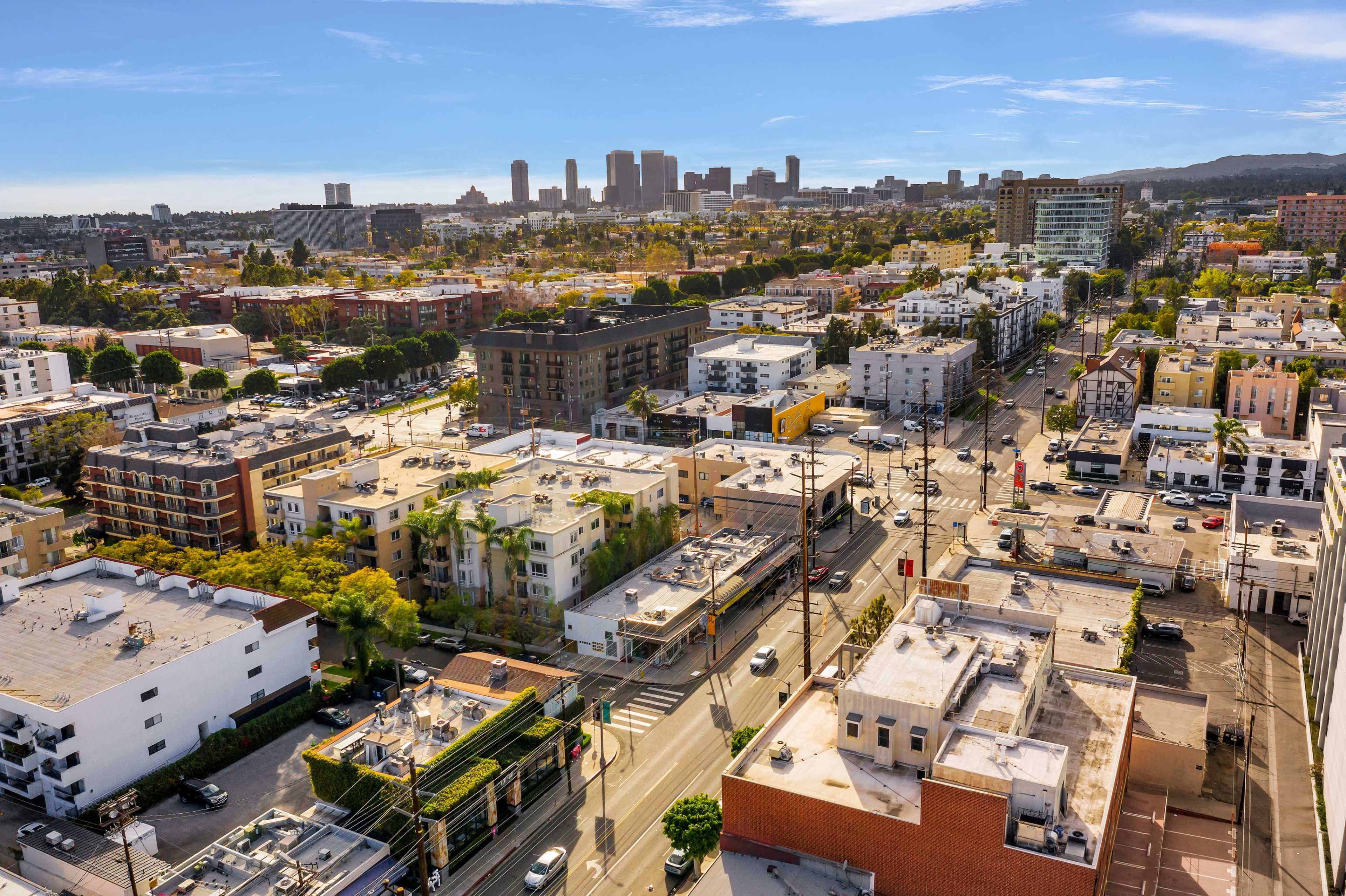 A wide view of a cityscape with various buildings and streets leading toward a skyline in the background.