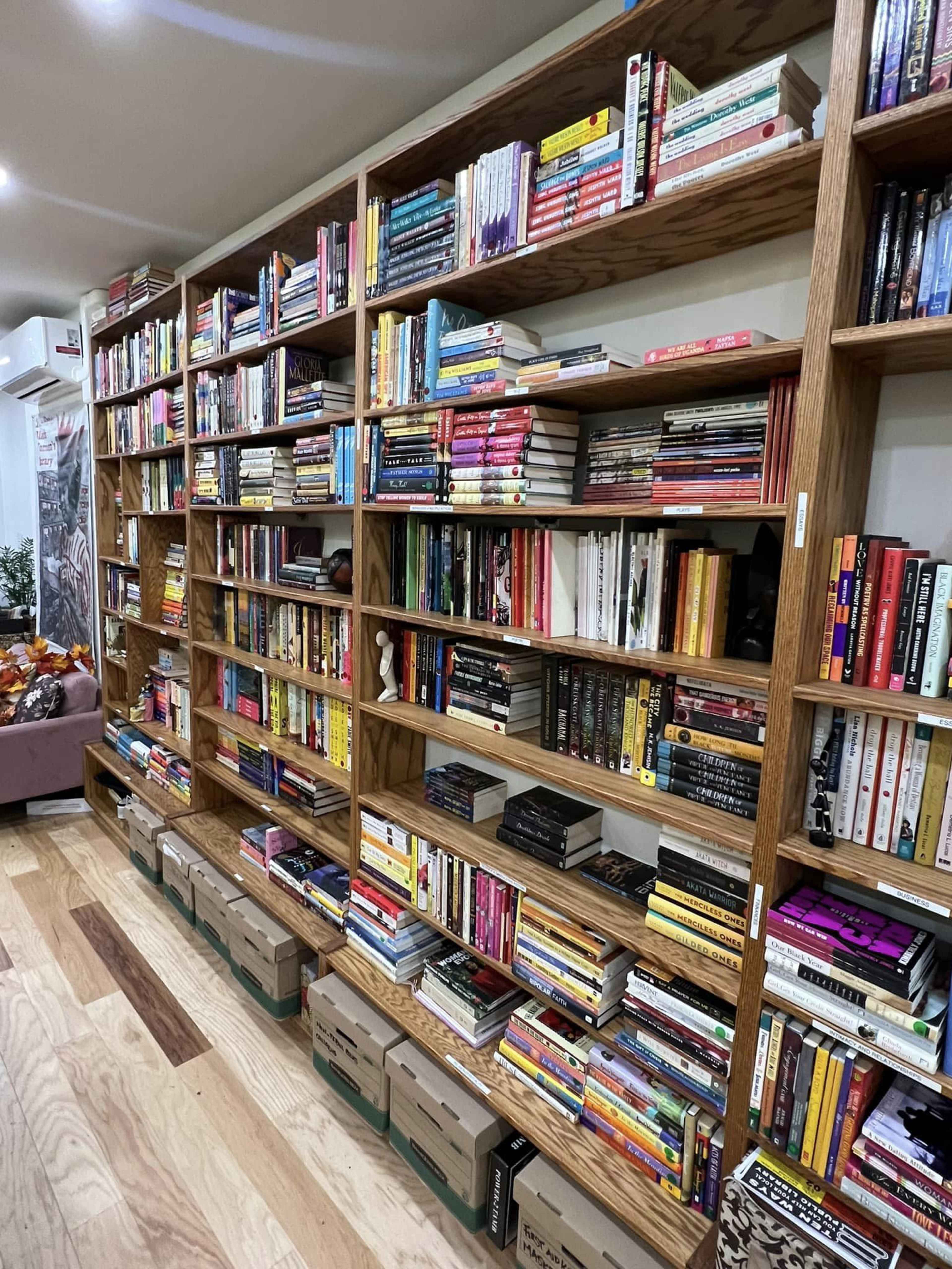 A wooden bookshelf filled with various books and organized storage boxes at the bottom.
