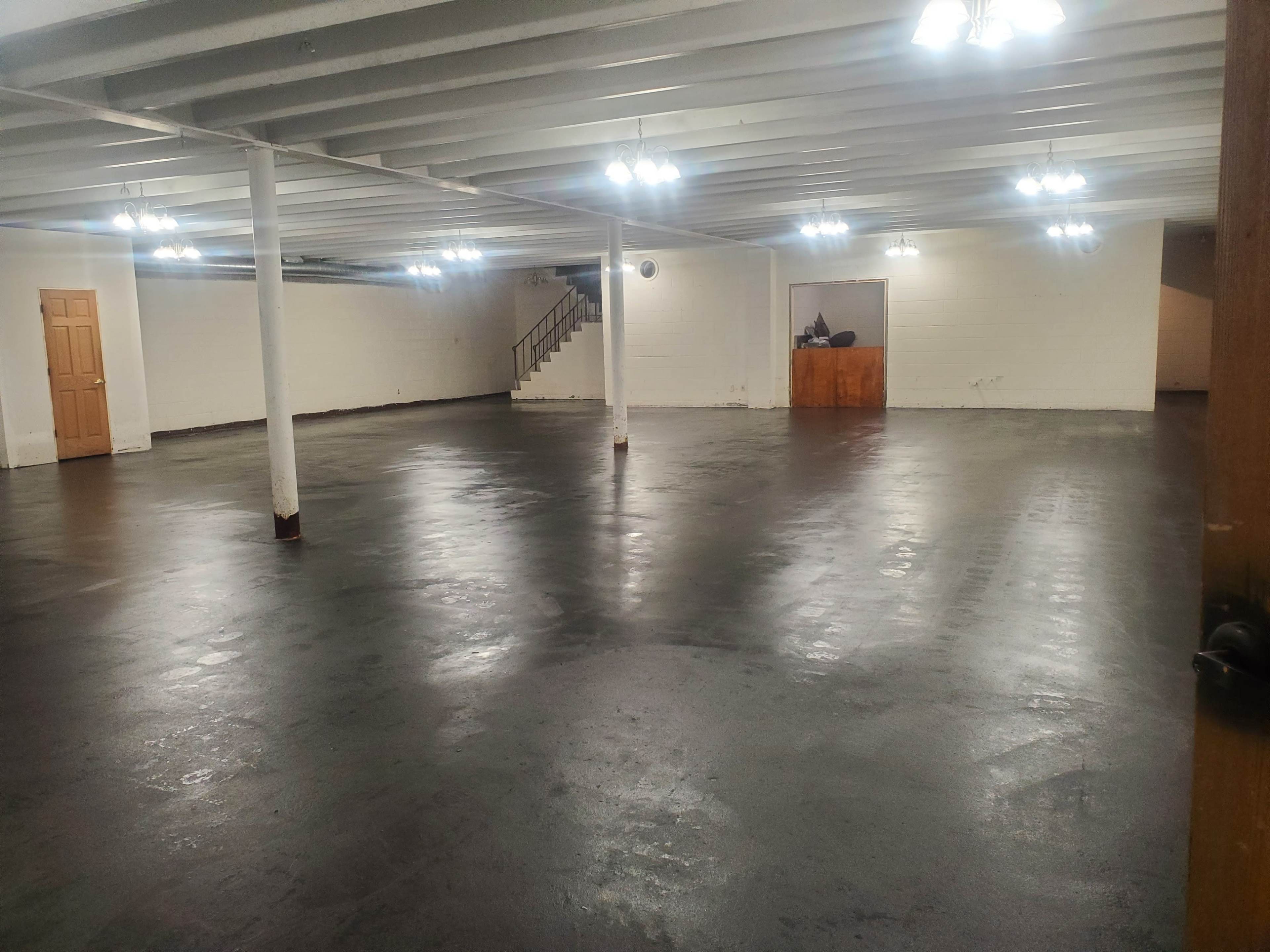 A spacious, empty basement with polished concrete floors and several overhead lights.