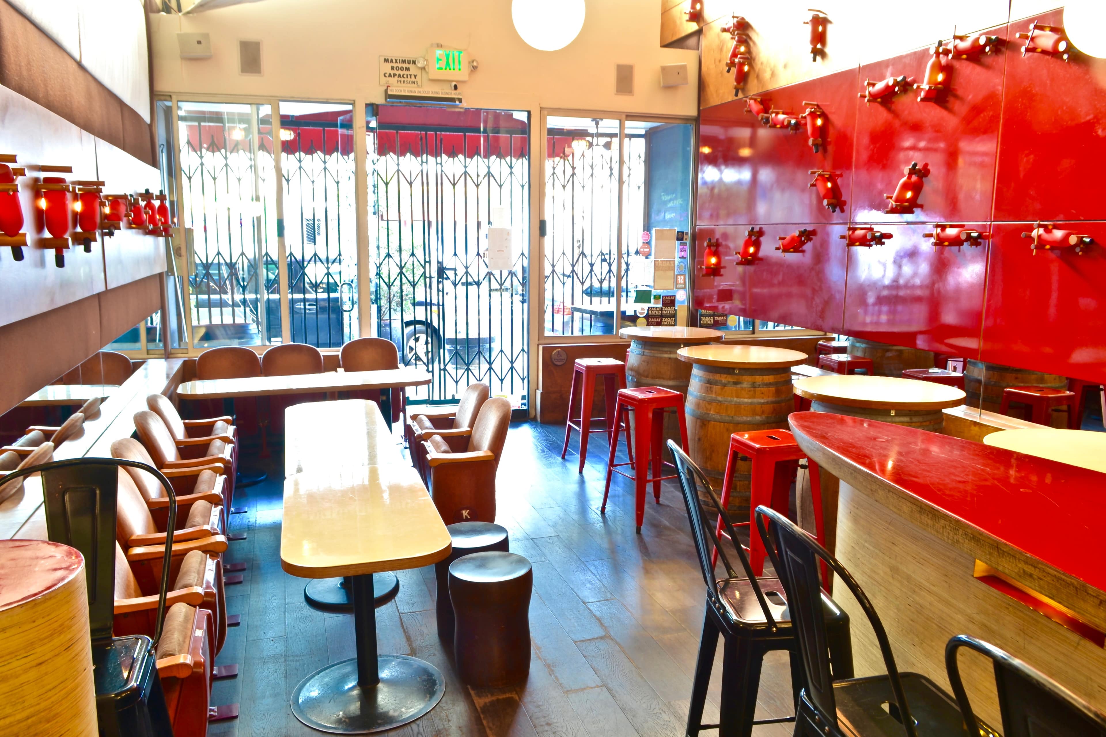 The interior of a modern café features red walls, various seating options, and a spacious layout with a bar area.