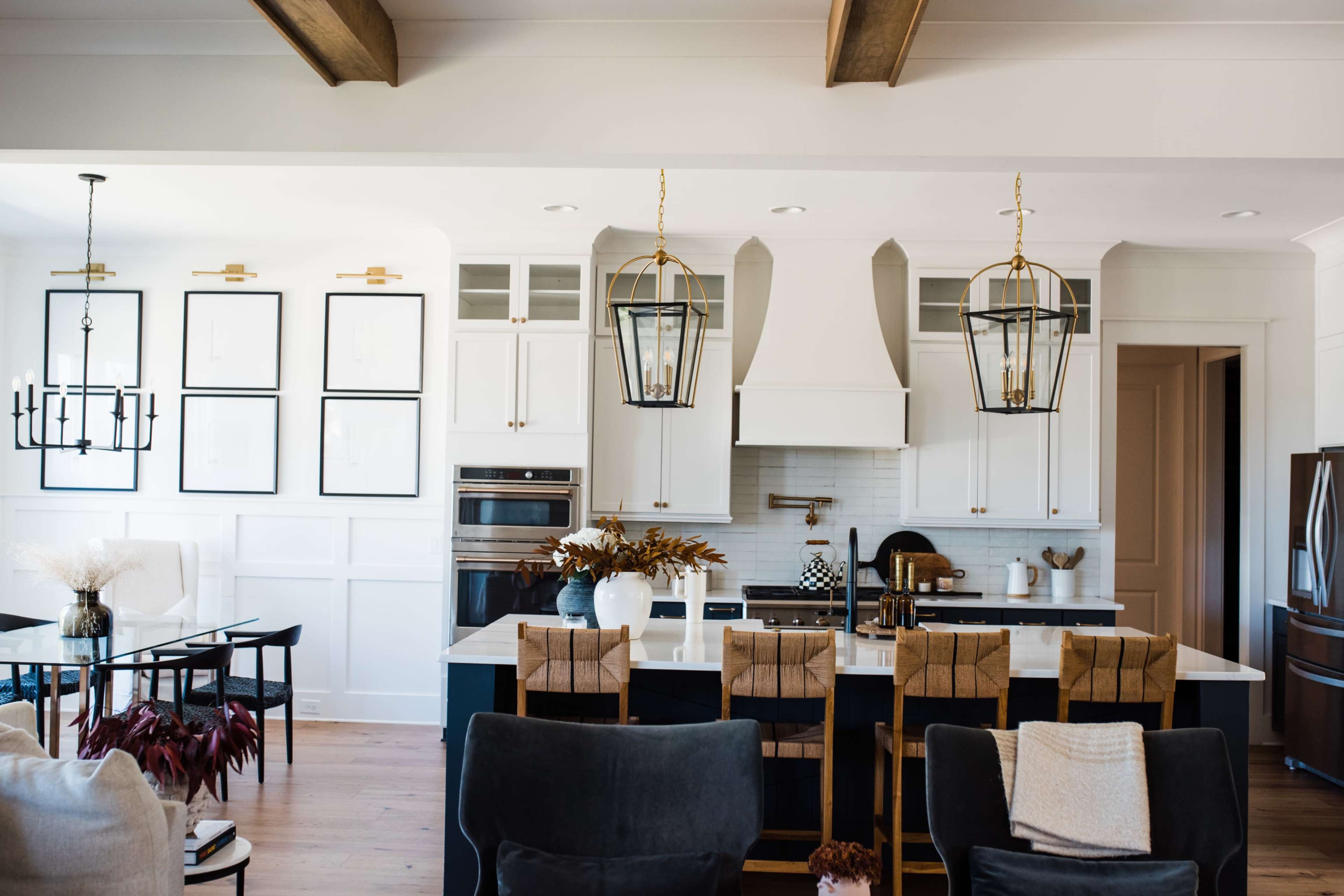A modern kitchen with white cabinetry, a large island with dark countertops, and two hanging pendant lights.