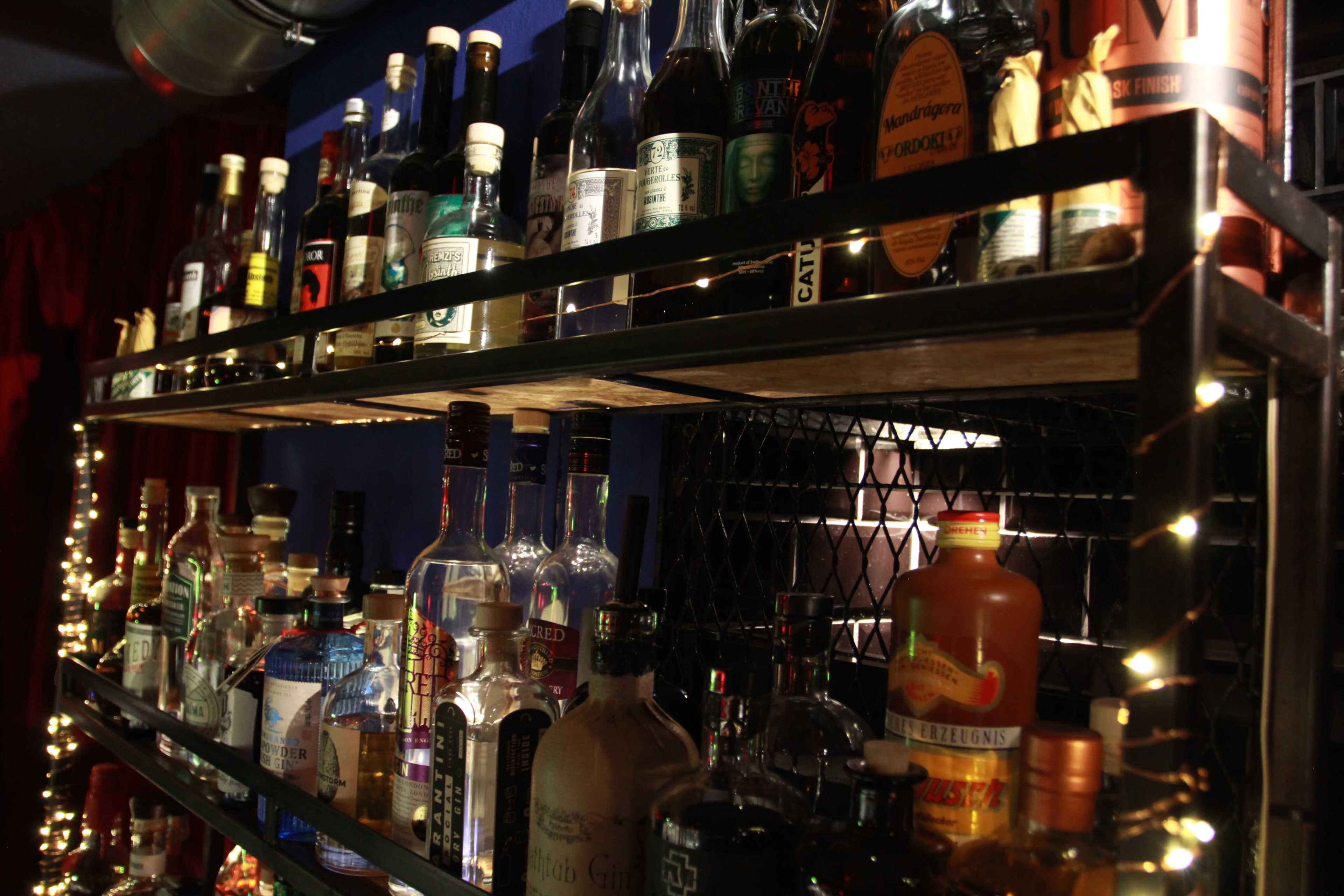 A dimly lit shelf filled with various bottles of spirits and liquors arranged neatly on display.