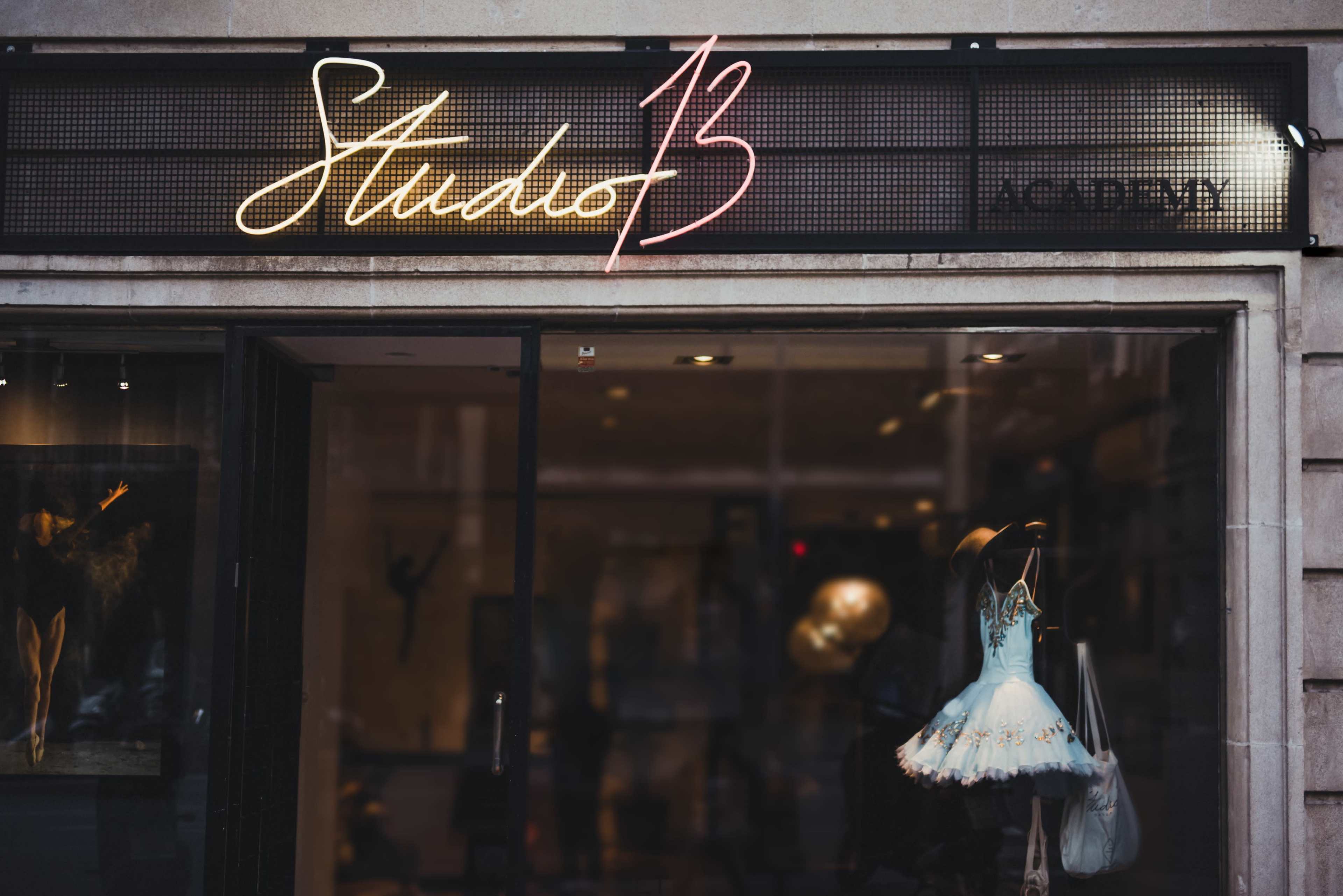 The storefront displays a neon sign reading "Studio 13" above a dress displayed in the window.