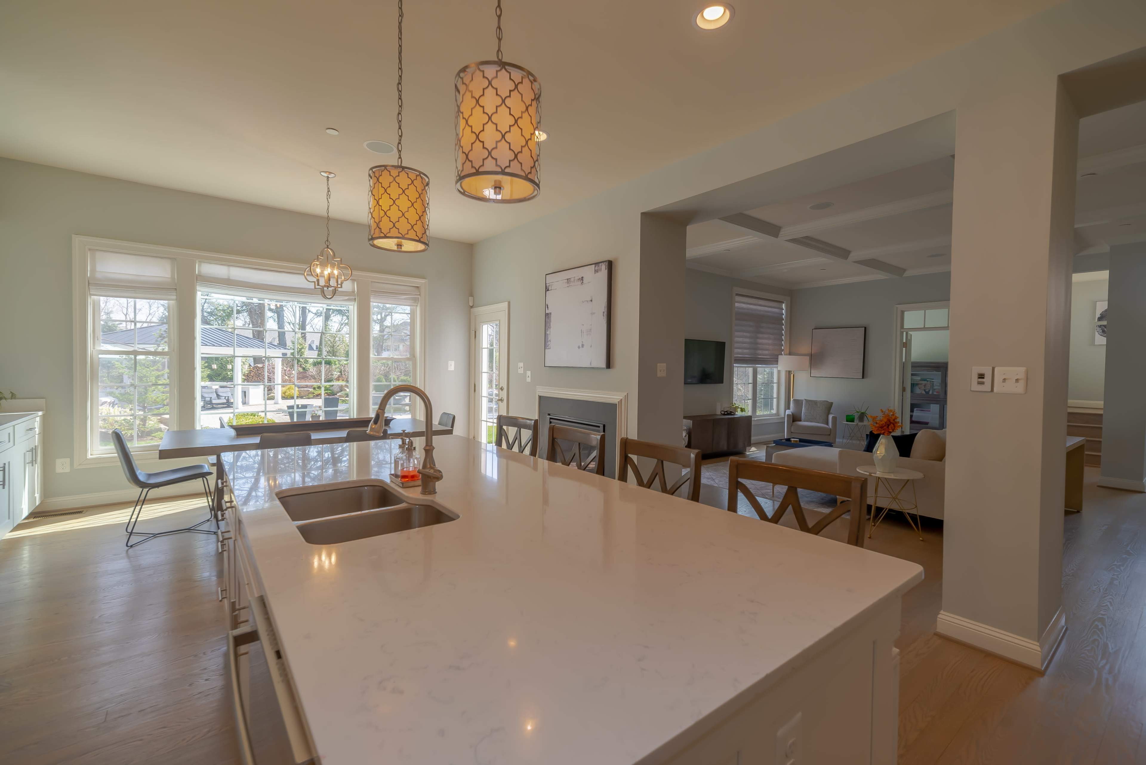 A modern kitchen with a marble island, pendant lights, and a dining area visible in an open-concept living space.