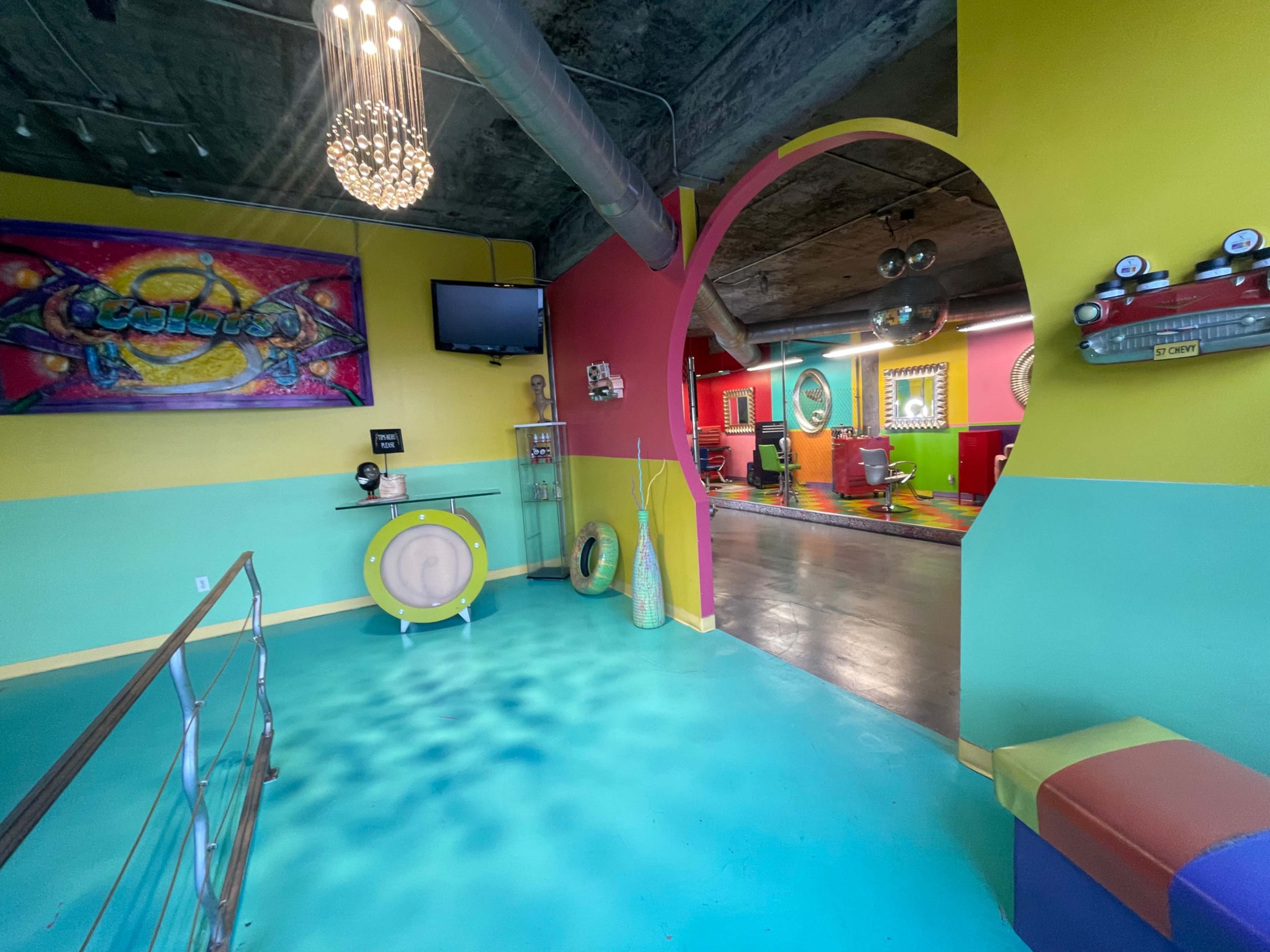 A colorful interior space featuring vibrant walls and unique furnishings, with a view into a room that appears to have a playful design.