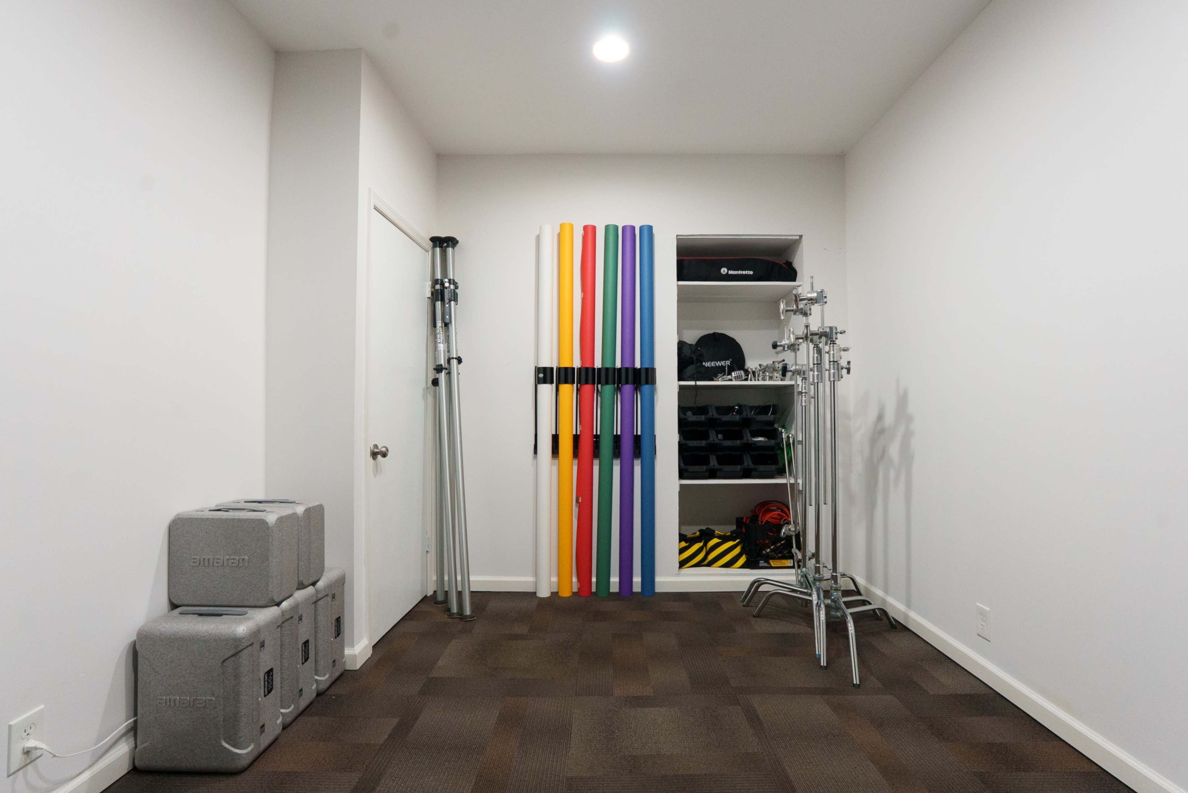 The room features a minimalistic design with gray foam blocks stacked in one corner, colorful vertical foam rods mounted on the wall, and metal equipment stands arranged on the opposite side.