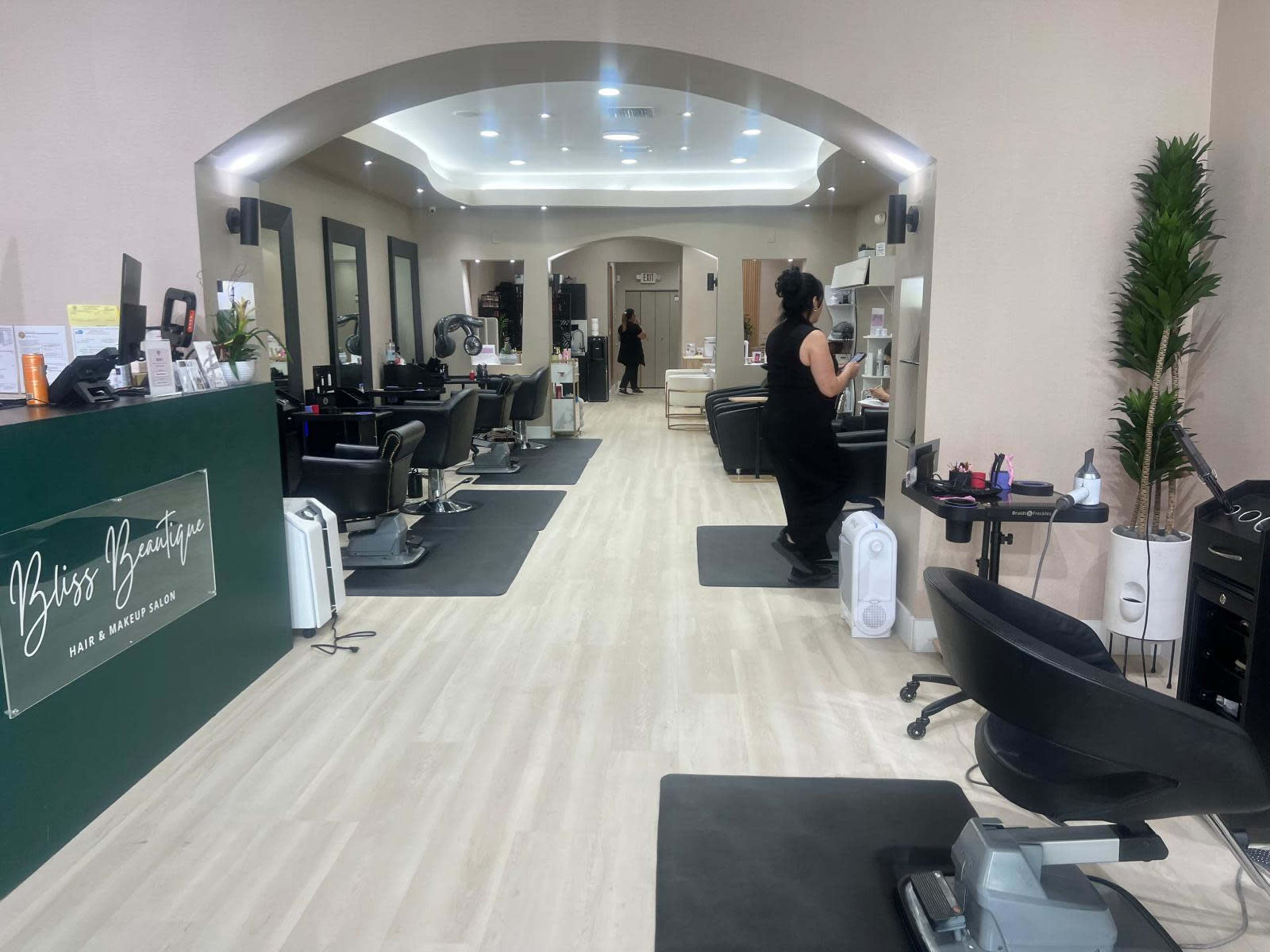 The image shows a modern hair and beauty salon with several styling stations and a reception area.