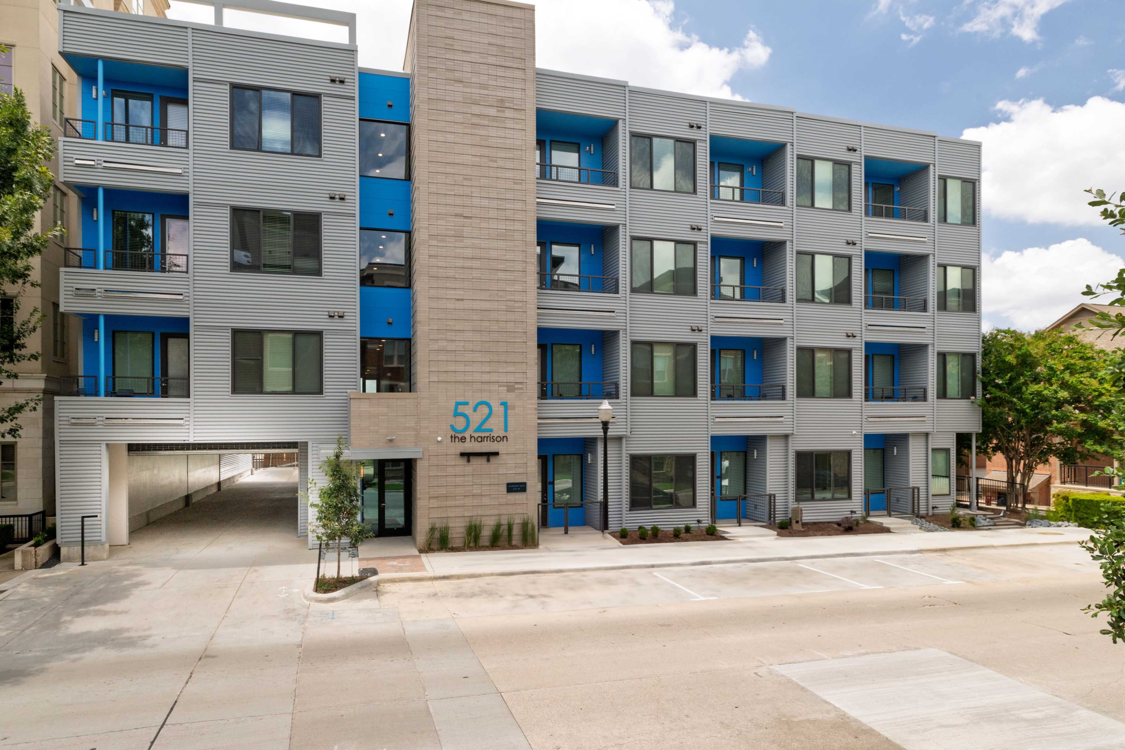 The image shows a modern three-story building with blue accents and large windows, labeled "521 the horizon," situated beside a paved street.