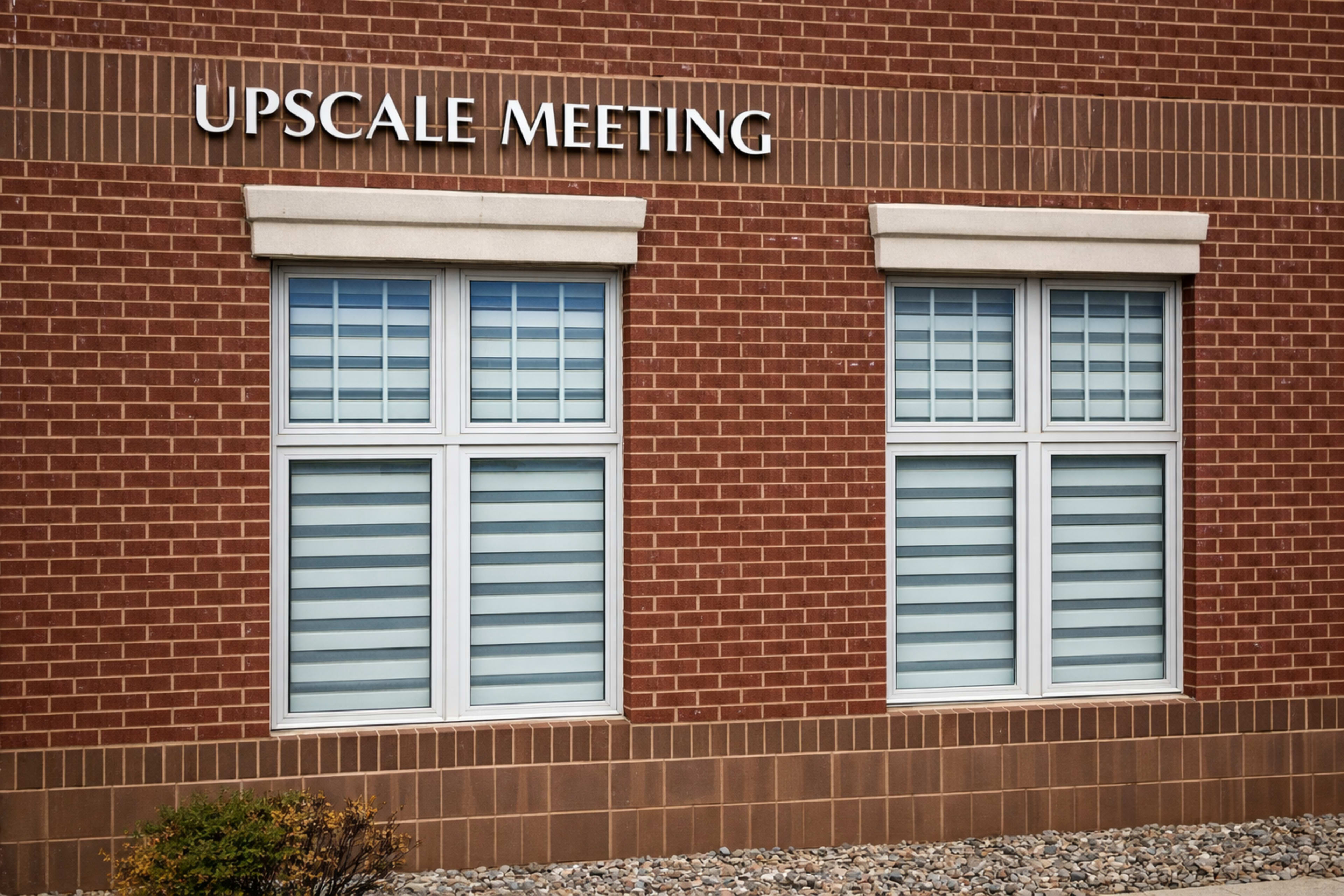 The image shows two windows on a brick building, with the words "UPSCAL MEETING" displayed above them.